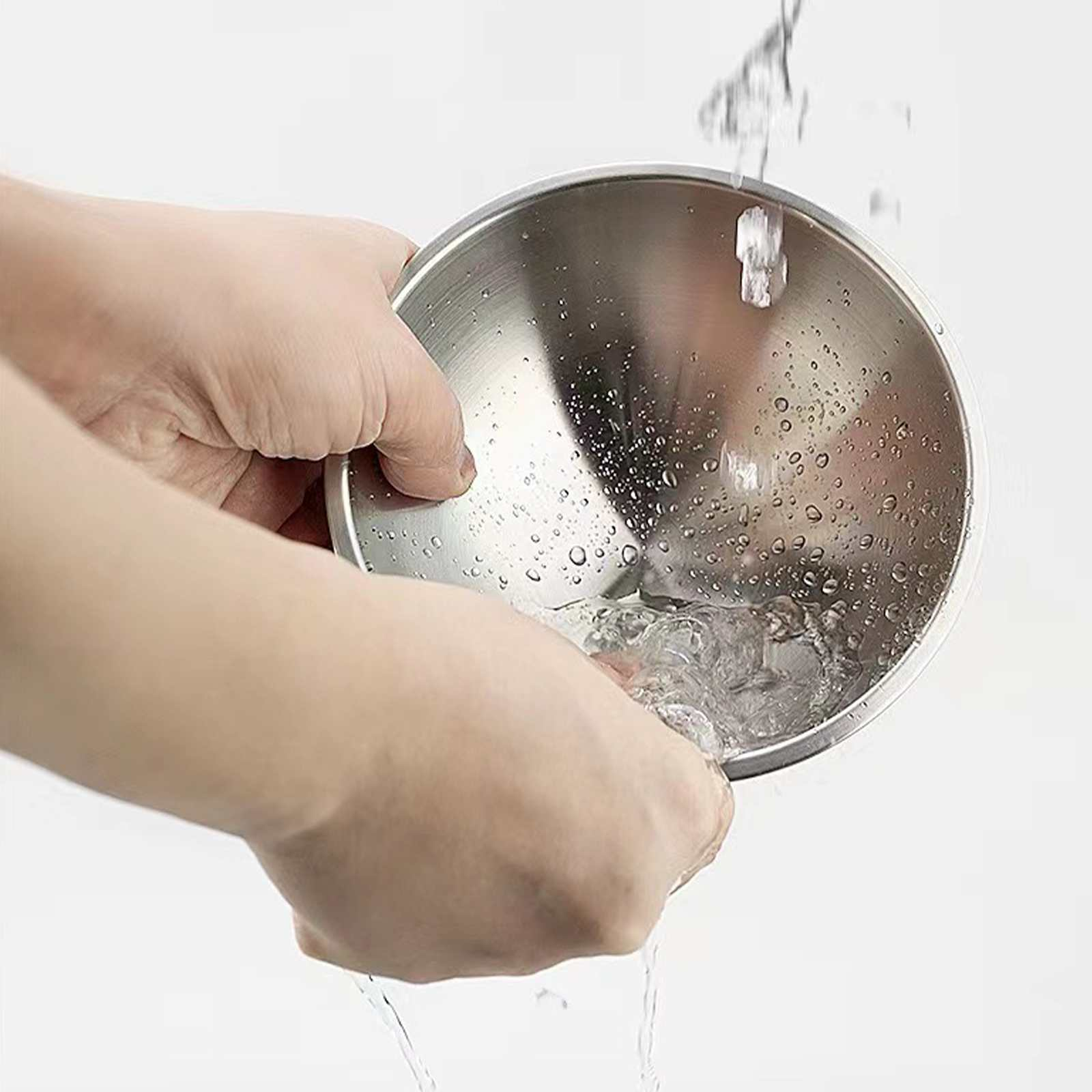 Hände halten eine Edelstahlschüssel unter fließendem Wasser. Wassertropfen auf der Schüssel. Weißer Hintergrund.