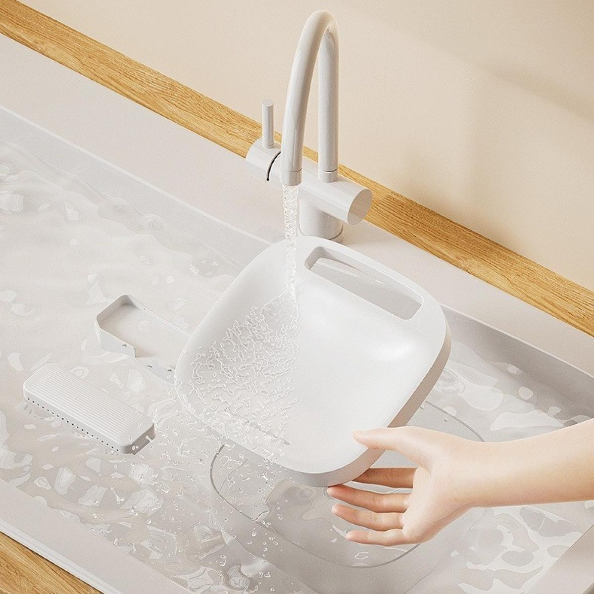 Ein weißes Waschbecken, in dem eine Hand ein weißes Becken unter einem laufenden Wasserhahn hält. Wasser füllt das Becken und die Umgebung.