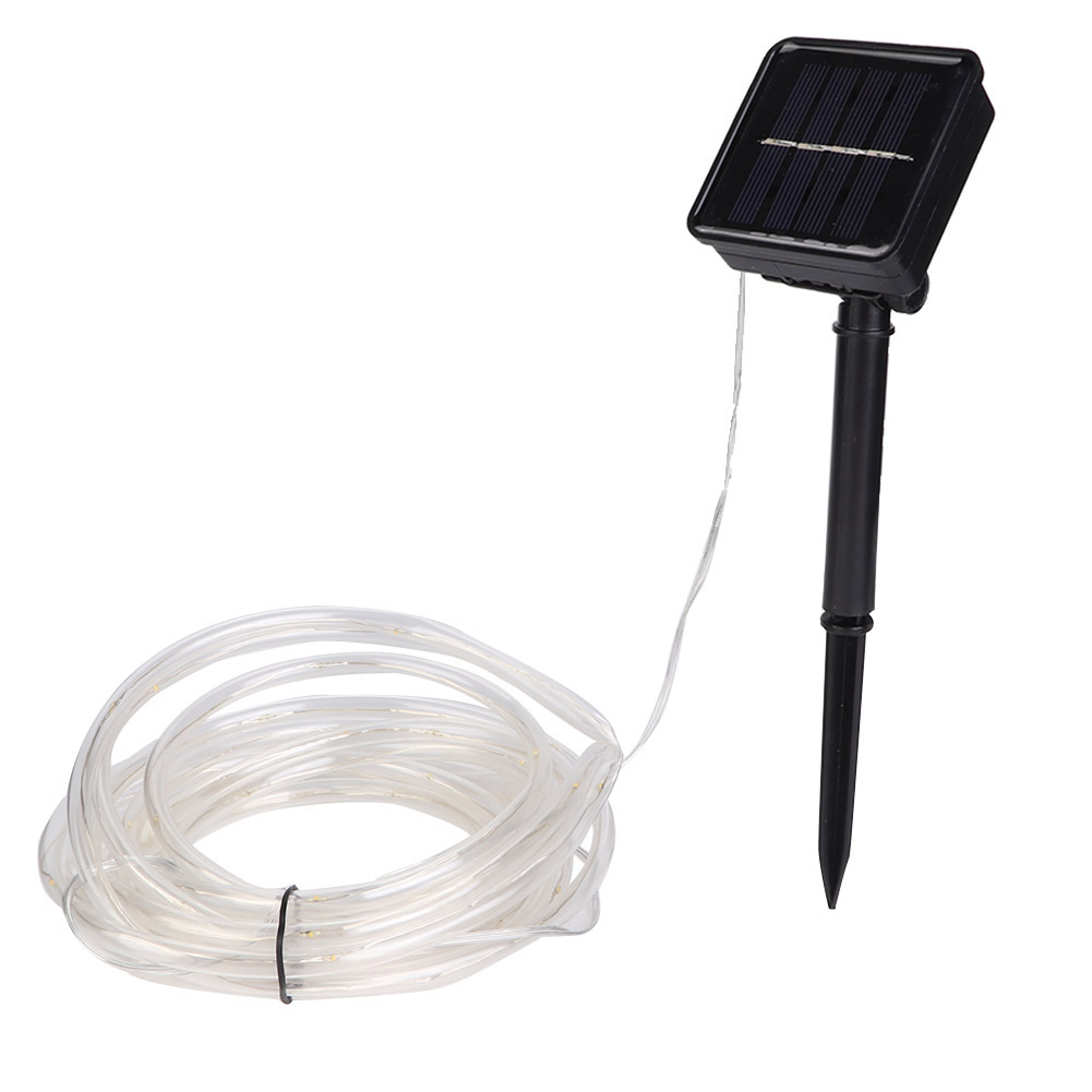 Eine solarbetriebene Lichterkette. Sie besteht aus einem Solarpanel, einem schwarzen Pfahl und einer aufgerollten transparenten Röhre mit kleinen Lichtern.