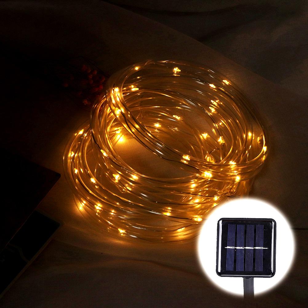 Zusammengeknüllte Lichterkette mit warmgelben Lichtern. Im Vordergrund befindet sich ein Solarpanel. Der Hintergrund ist dunkel und weich.