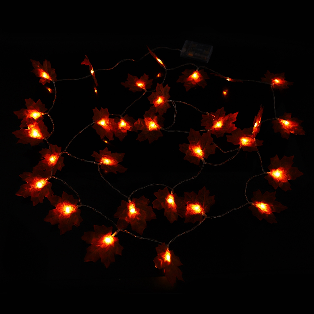 Eine Lichterkette mit orangefarbenen, blattförmigen Lichtern auf dunklem Hintergrund. Die Lichter leuchten und erzeugen ein warmes Leuchten.