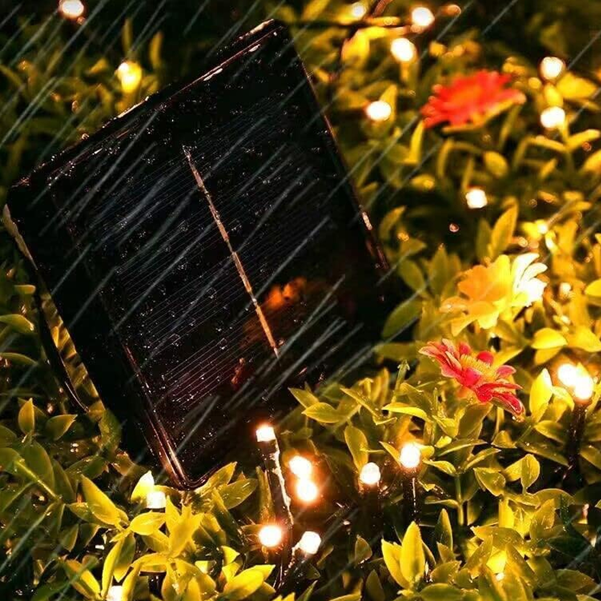 Ein Solarpanel in einem Garten mit Lichterketten und Blumen. Es regnet. Das Panel ist schwarz und abgewinkelt.