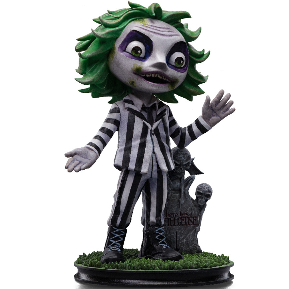 Una statuetta di Beetlejuice. Ha i capelli verdi, un abito a righe bianche e nere e si trova vicino a una lapide con la scritta "Beetlejuice".