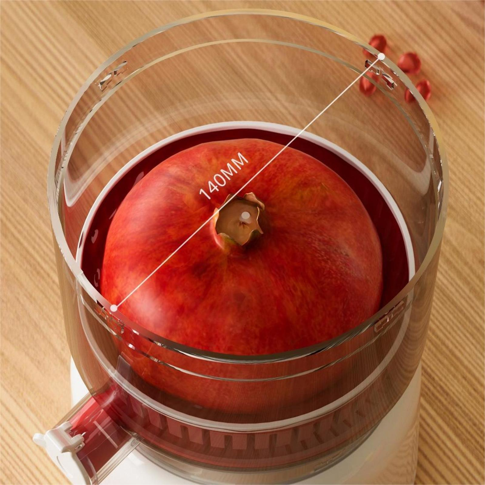 Ein roter Granatapfel in einem Entsafter. Eine weiße Linie zeigt 140 mm an. Holziger Hintergrund. Einige Granatapfelkerne oben.