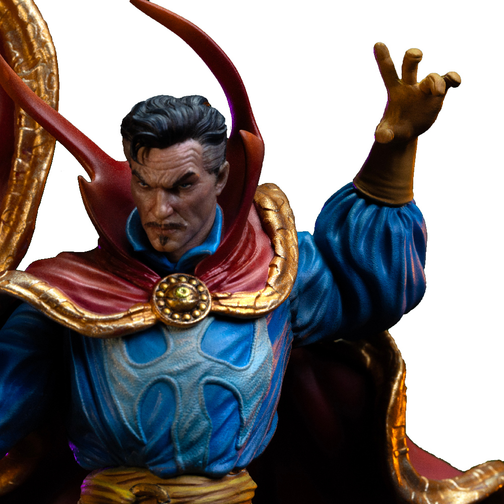 Statue von Doctor Strange in blauen Gewändern und rotem Umhang, mit goldenem Emblem auf der Brust. Er hebt die Hand zu einer Geste.