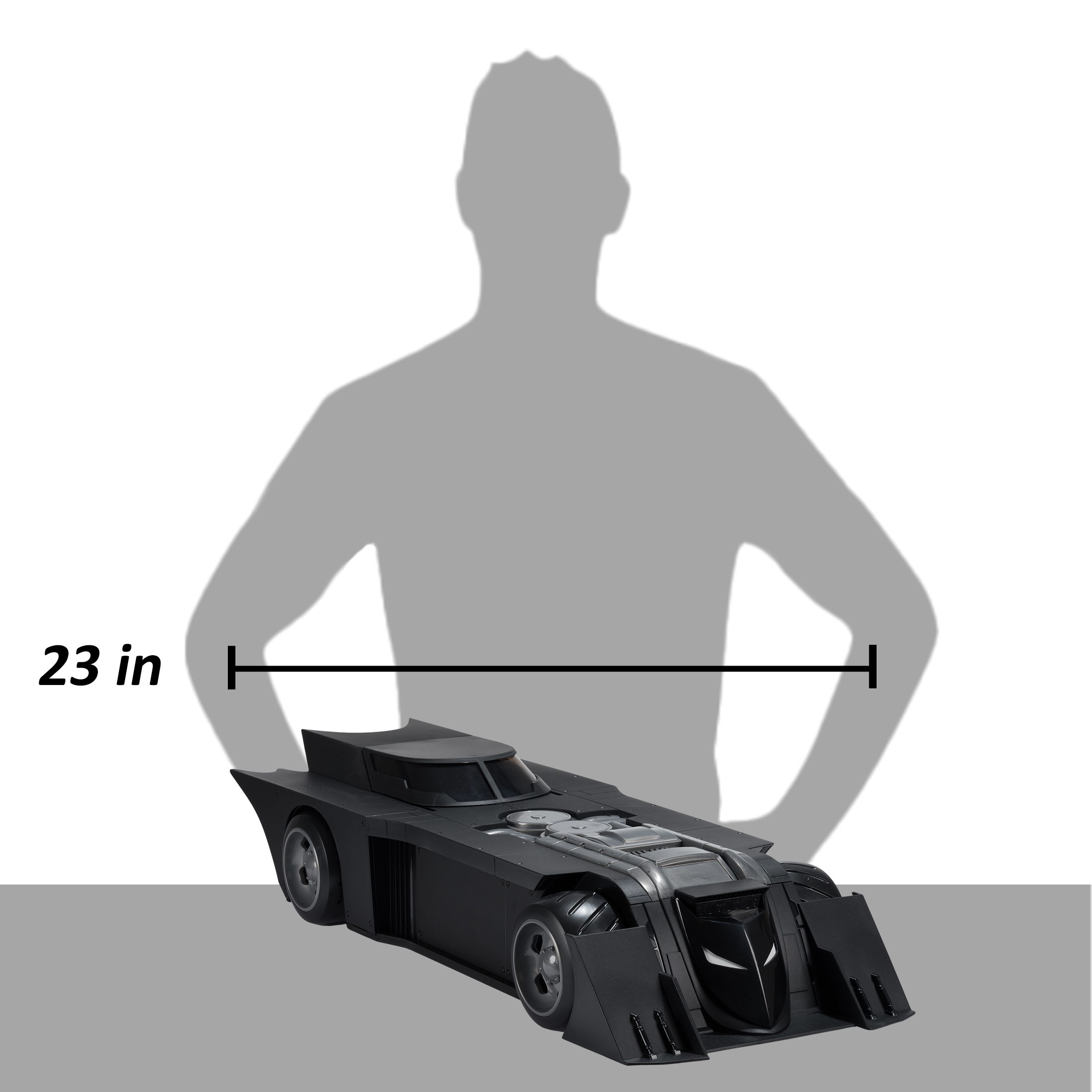 Schwarzes Batmobil-Spielzeug mit einer menschlichen Silhouette dahinter. Das Auto ist 23 Zoll lang, auf grauem und weißem Hintergrund.