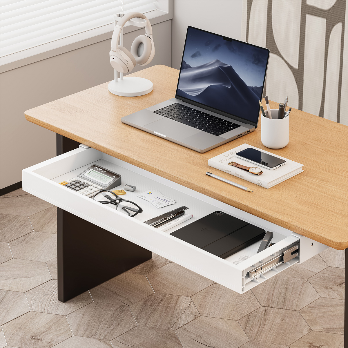 Una scrivania in legno con un laptop, cuffie e un cassetto. Il cassetto contiene forniture per ufficio, occhiali e un tablet. Lo sfondo è sfocato.