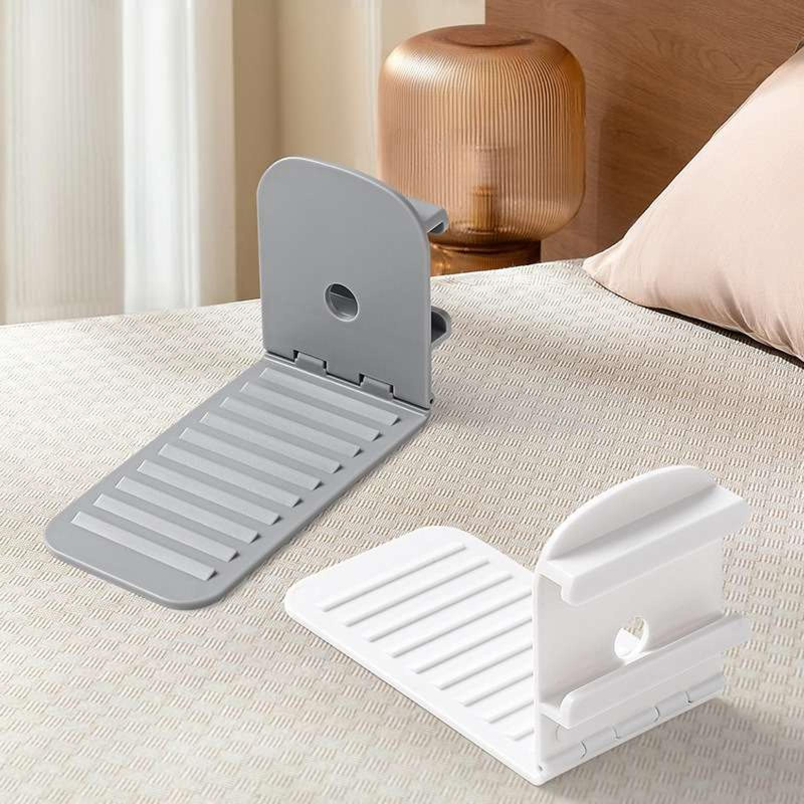 Zwei Bettstützen, grau und weiß, auf einem Bett. Eine Lampe und ein Kissen sind im Hintergrund.