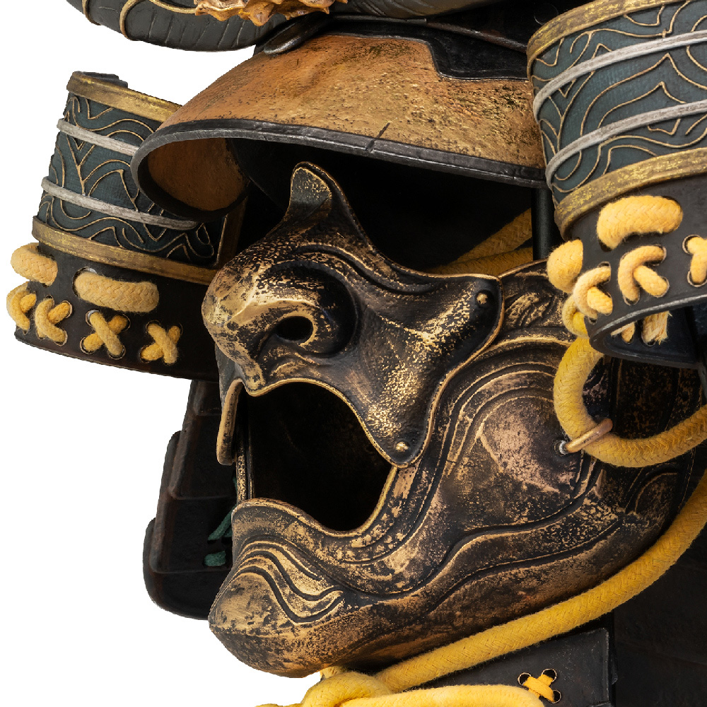 Nahaufnahme eines Samurai-Helms mit gold-schwarzem Farbschema. Details umfassen Maske, Schulterschutz und dekoratives Seil.