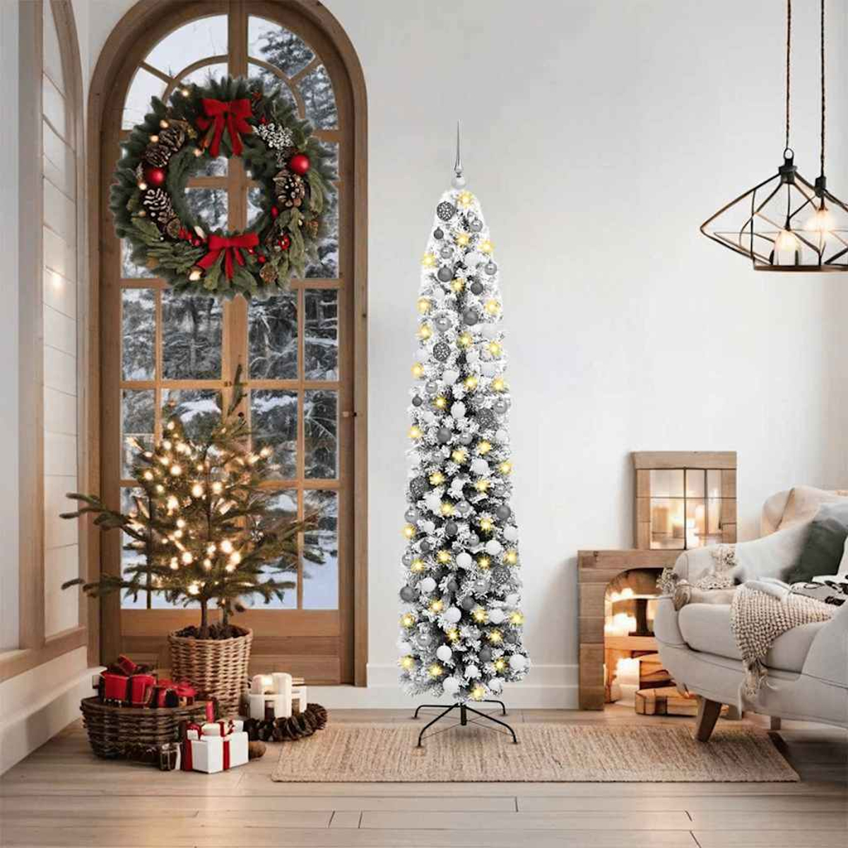 Ein hoher, schlanker Weihnachtsbaum mit Lichtern und Ornamenten steht in der Nähe eines Fensters mit einem Kranz. Ein kleiner Baum und Geschenke sind davor.