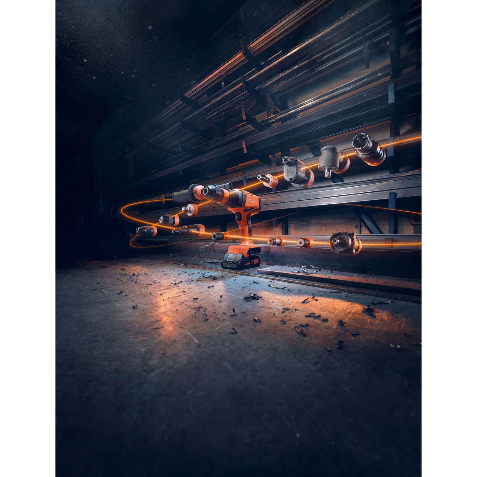 Un trapano arancione con accessori e linee luminose in un'officina buia. Tubi metallici sullo sfondo.