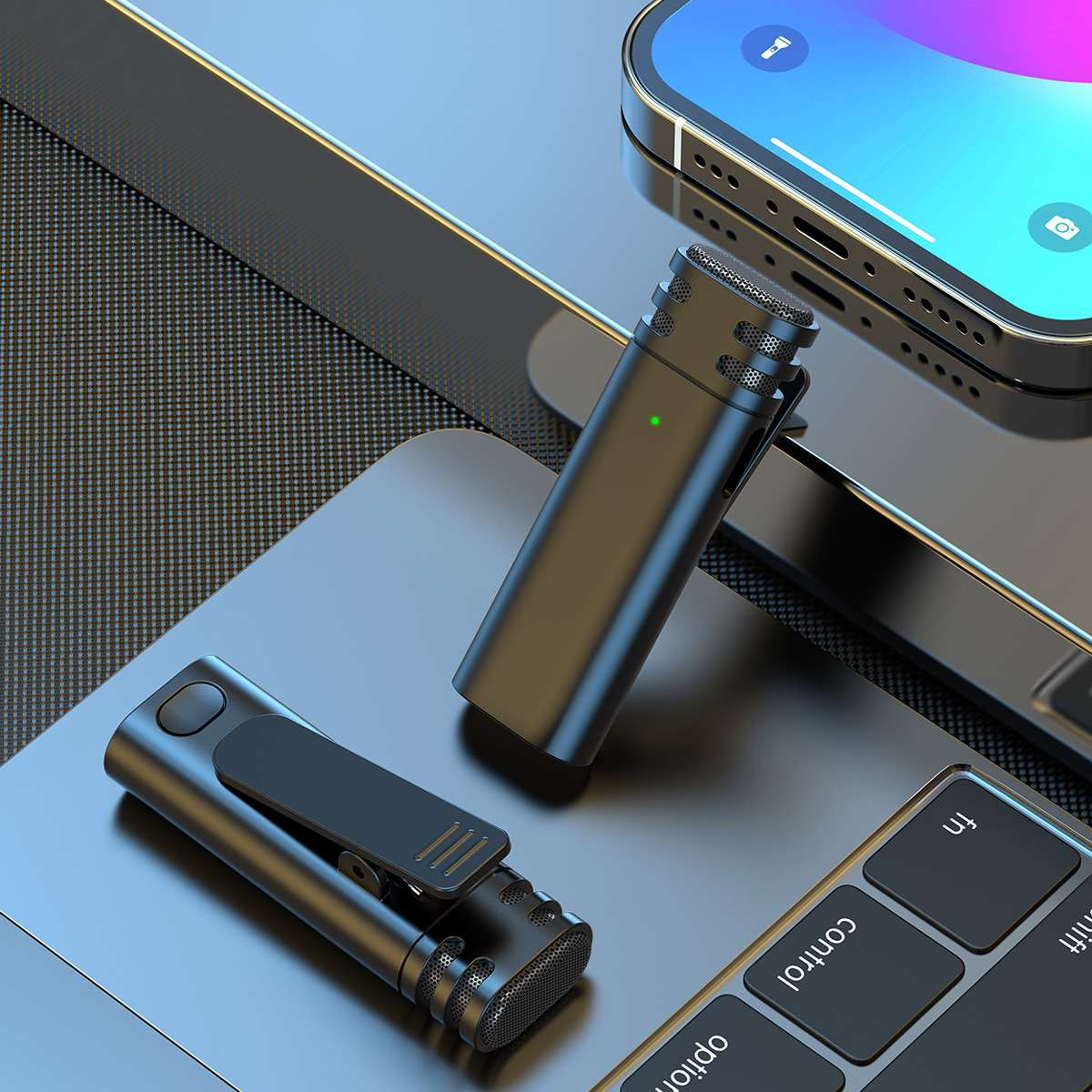 Zwei schwarze Mikrofone auf einer Laptop-Tastatur, in der Nähe eines Smartphones. Ein Mikrofon hat einen Clip.