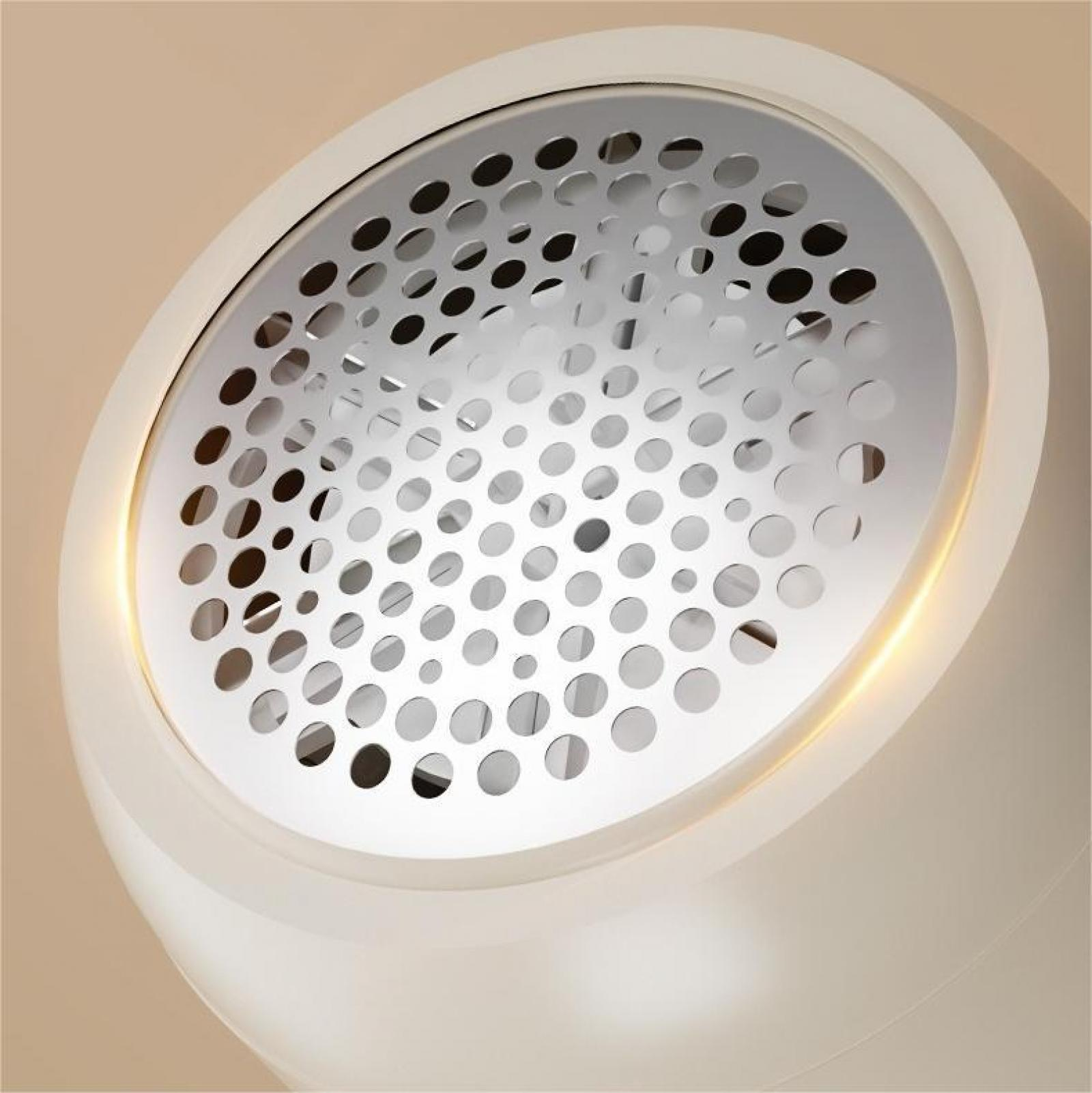 Nahaufnahme eines weißen, kreisförmigen Objekts mit perforierter Metalloberseite. Der Hintergrund ist beige. Licht scheint.