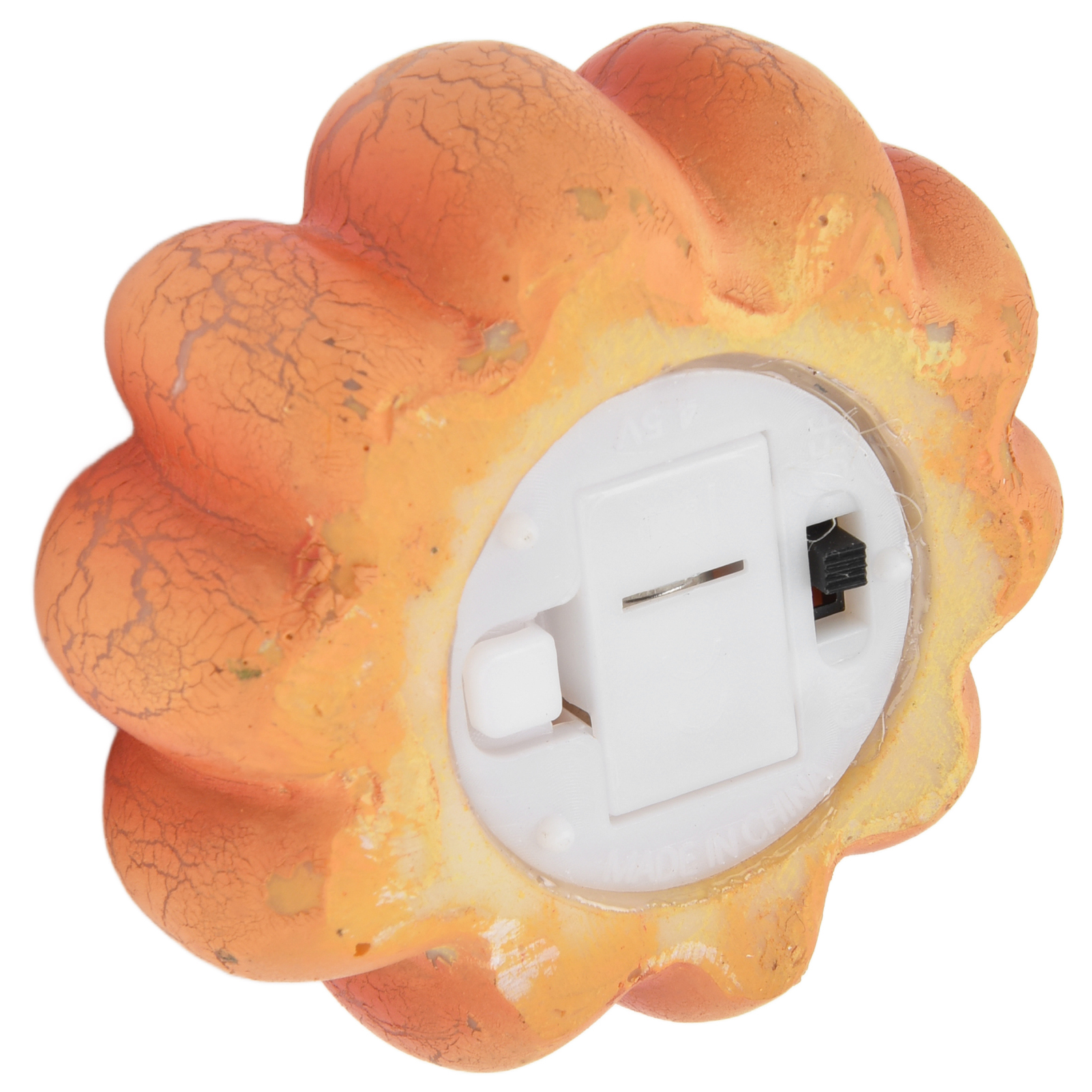 Orangefarbene Kürbisdekoration mit weißer Basis, Schalter und Batteriefach. Der Kürbis hat eine rissige Textur.