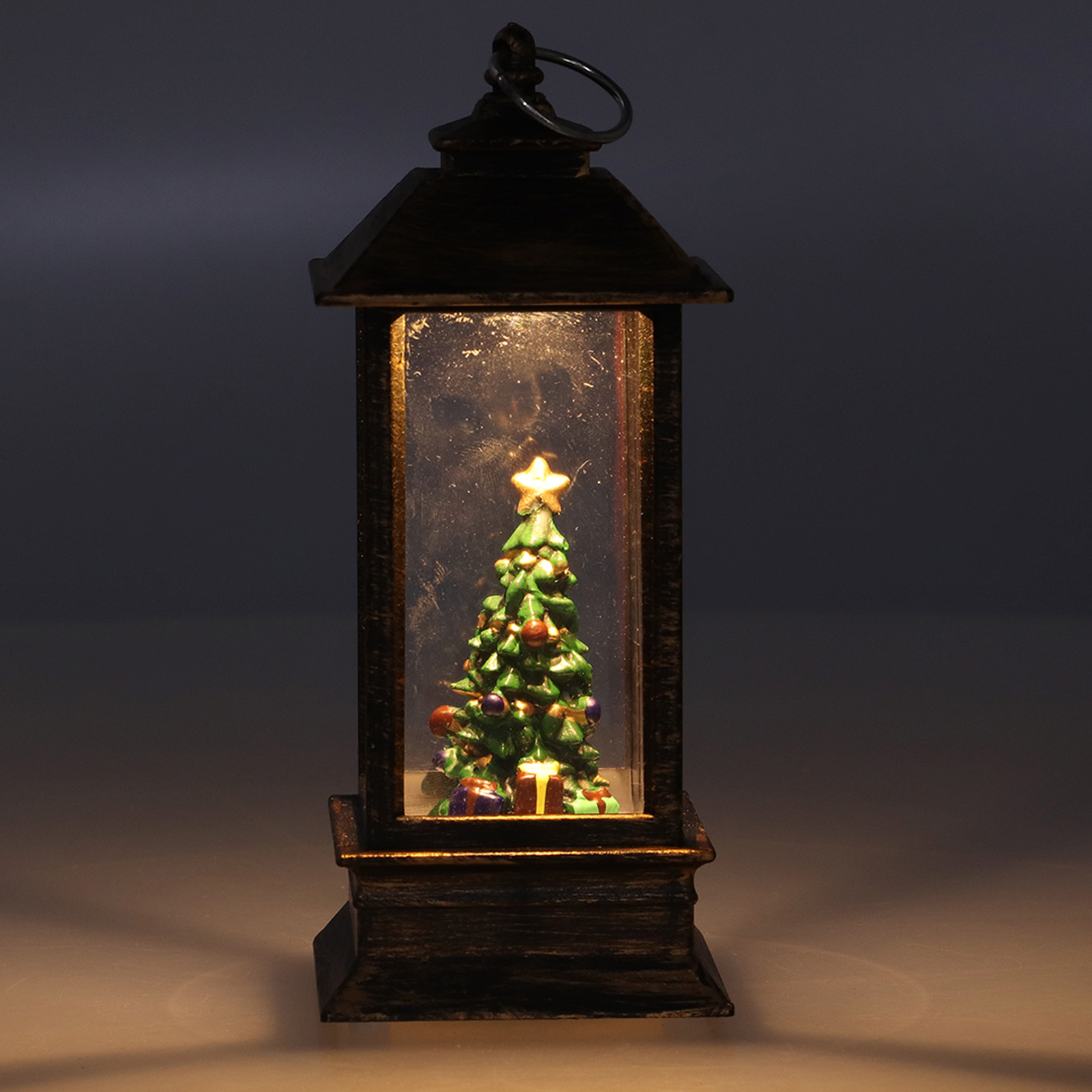 Eine Weihnachtslaterne mit einem Baum darin. Der Baum hat Ornamente und einen Stern. Es ist eine festliche und dekorative Szene.