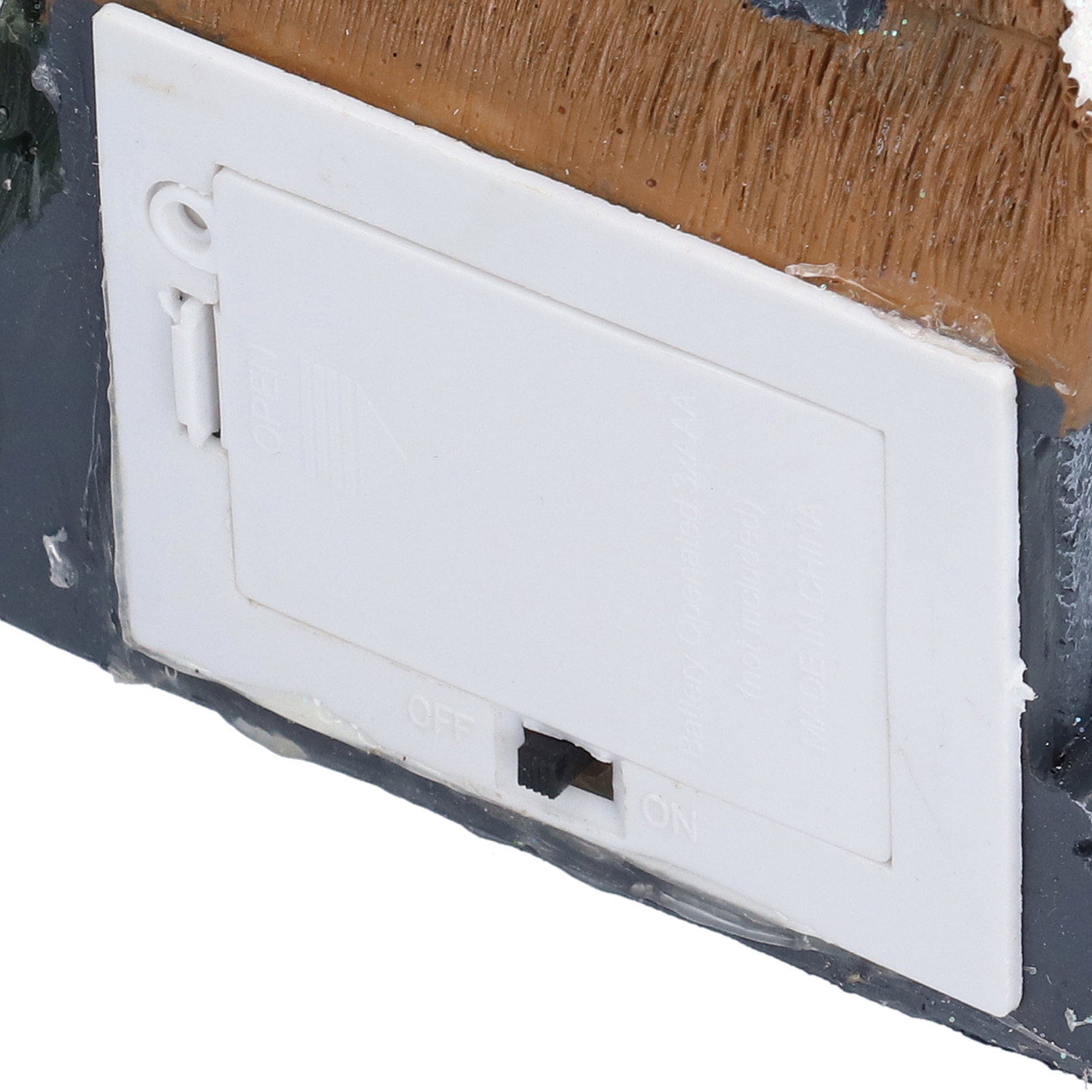 Nahaufnahme einer weißen Batteriefachklappe mit Ein-/Ausschalter und den Wörtern 'OPEN' und 'OFF'.