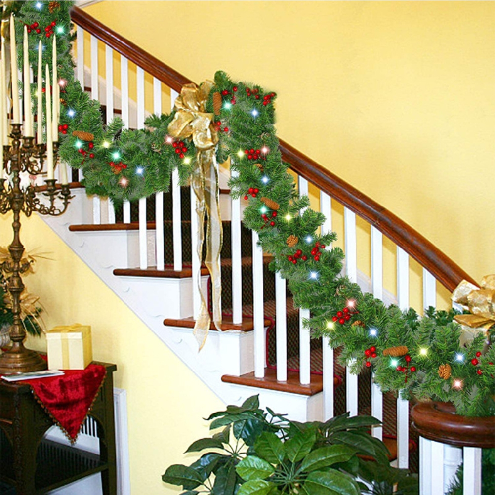 Eine dekorierte Treppe mit Girlande, Lichtern, Schleifen und Kerzen. Die Szene hat ein Weihnachtsthema mit grünen und roten Dekorationen.