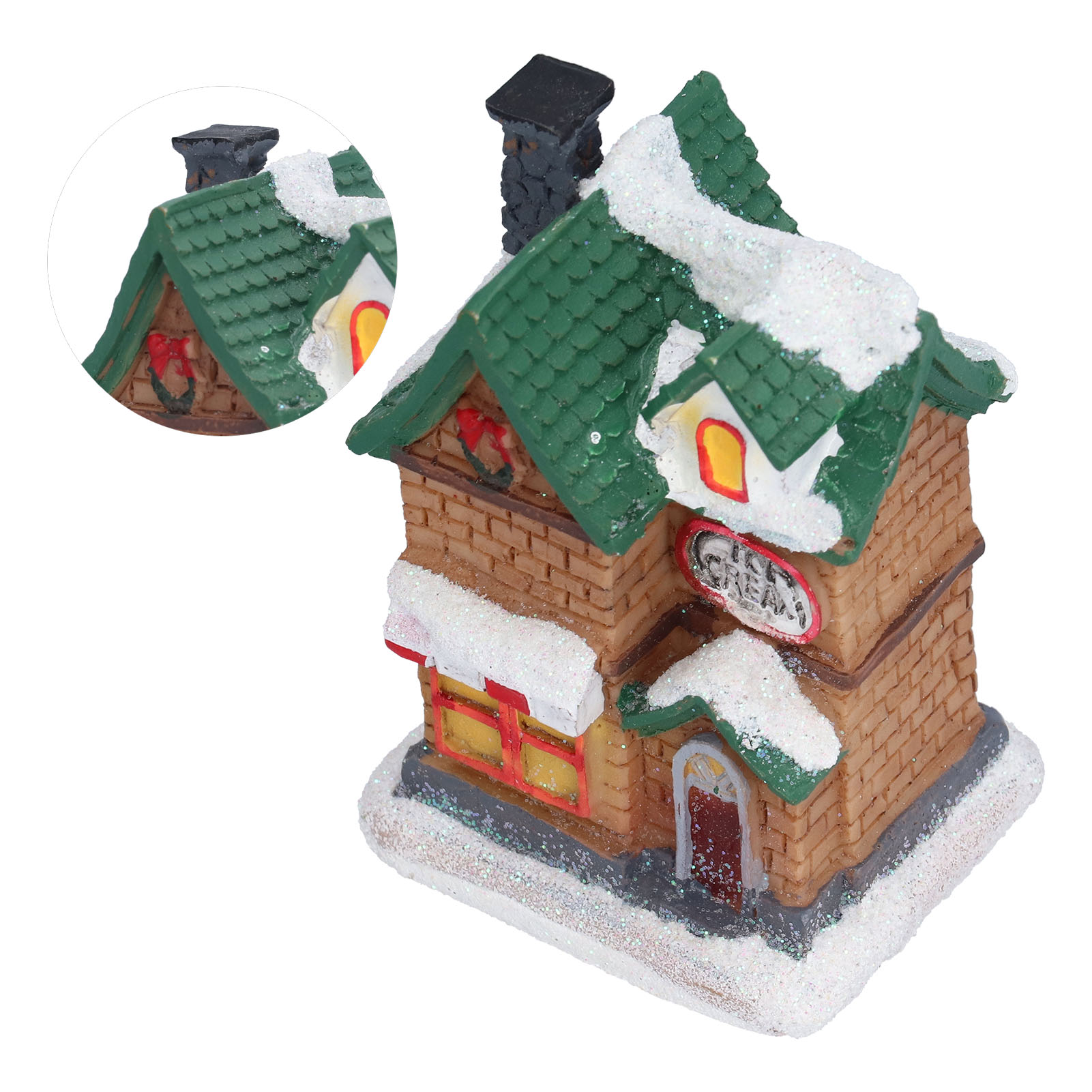 Ein Miniatur-Weihnachtshaus mit Schnee auf dem Dach. Es hat ein grünes Dach, braune Wände und einen schwarzen Schornstein.