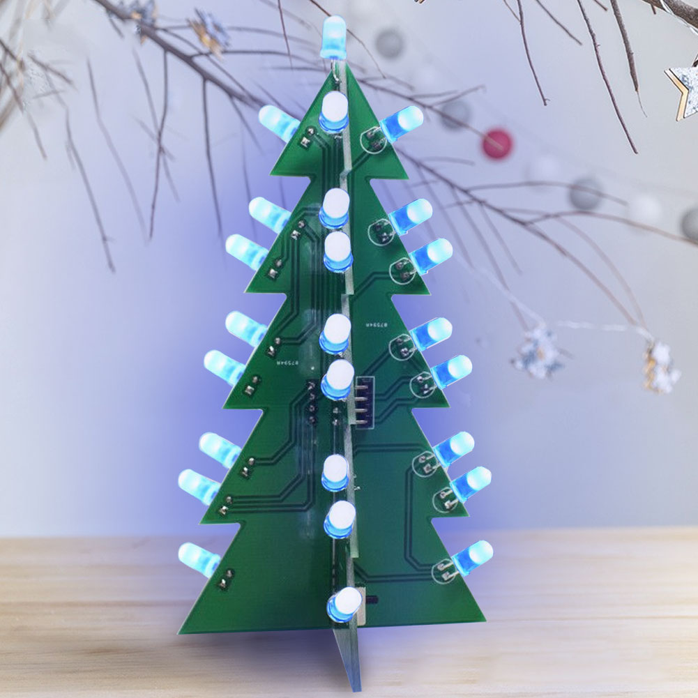 Ein grüner Weihnachtsbaum aus Leiterplatten mit blauen und weißen Lichtern steht auf einer Holzoberfläche. Der Hintergrund hat Dekorationen.