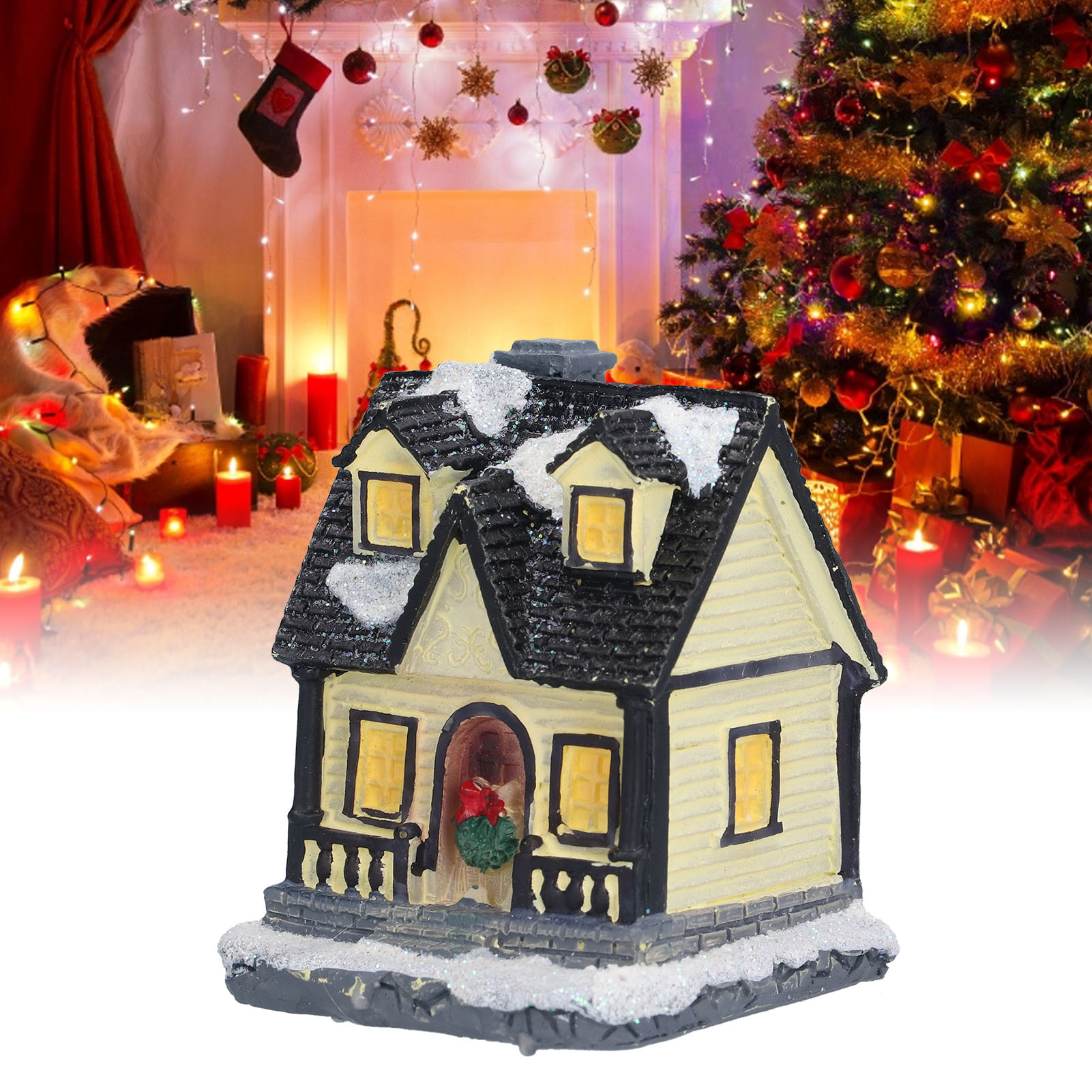 Ein Miniatur-Weihnachtshaus mit Schnee auf dem Dach, vor einem geschmückten Kamin und Weihnachtsbaum.