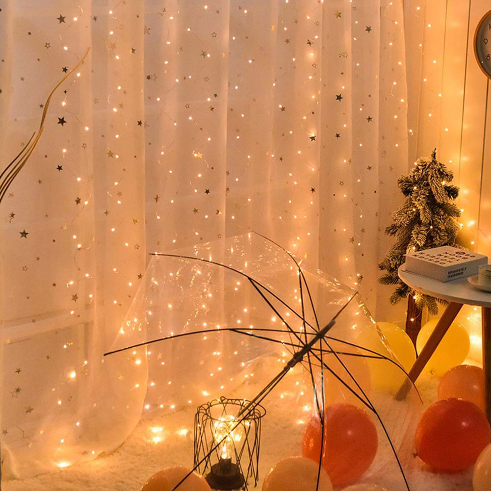 Eine beleuchtete Szene mit einem durchsichtigen Regenschirm, Lichterketten, Luftballons und einem kleinen Weihnachtsbaum.