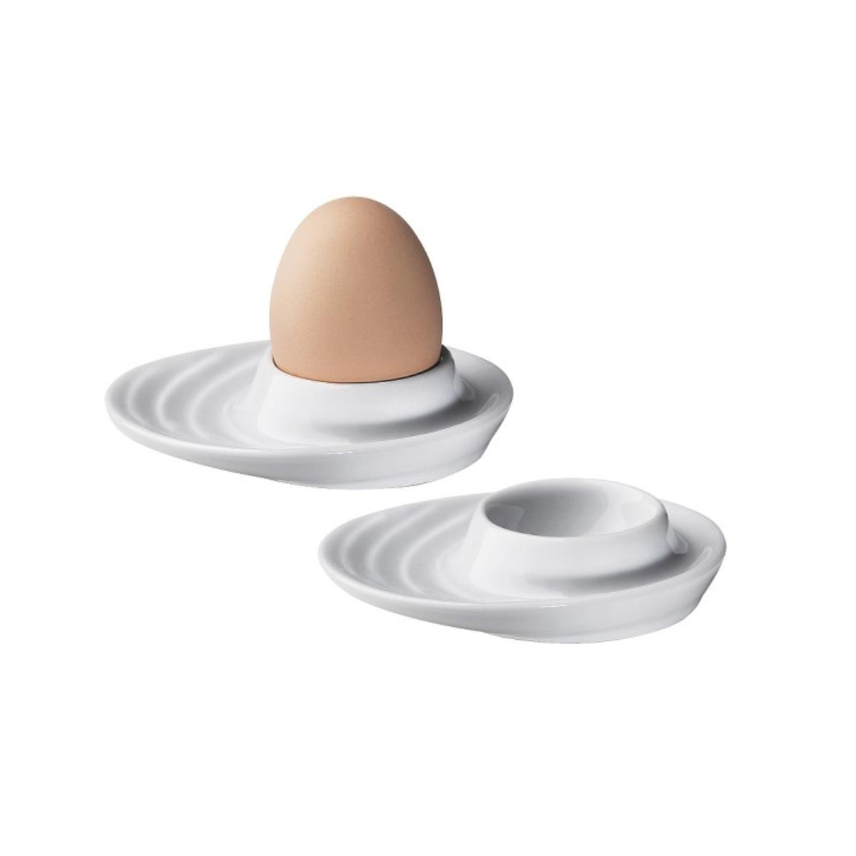 Due portauova in ceramica bianca, uno con un uovo marrone. Entrambe le tazze hanno un design ondulato. Sfondo bianco.