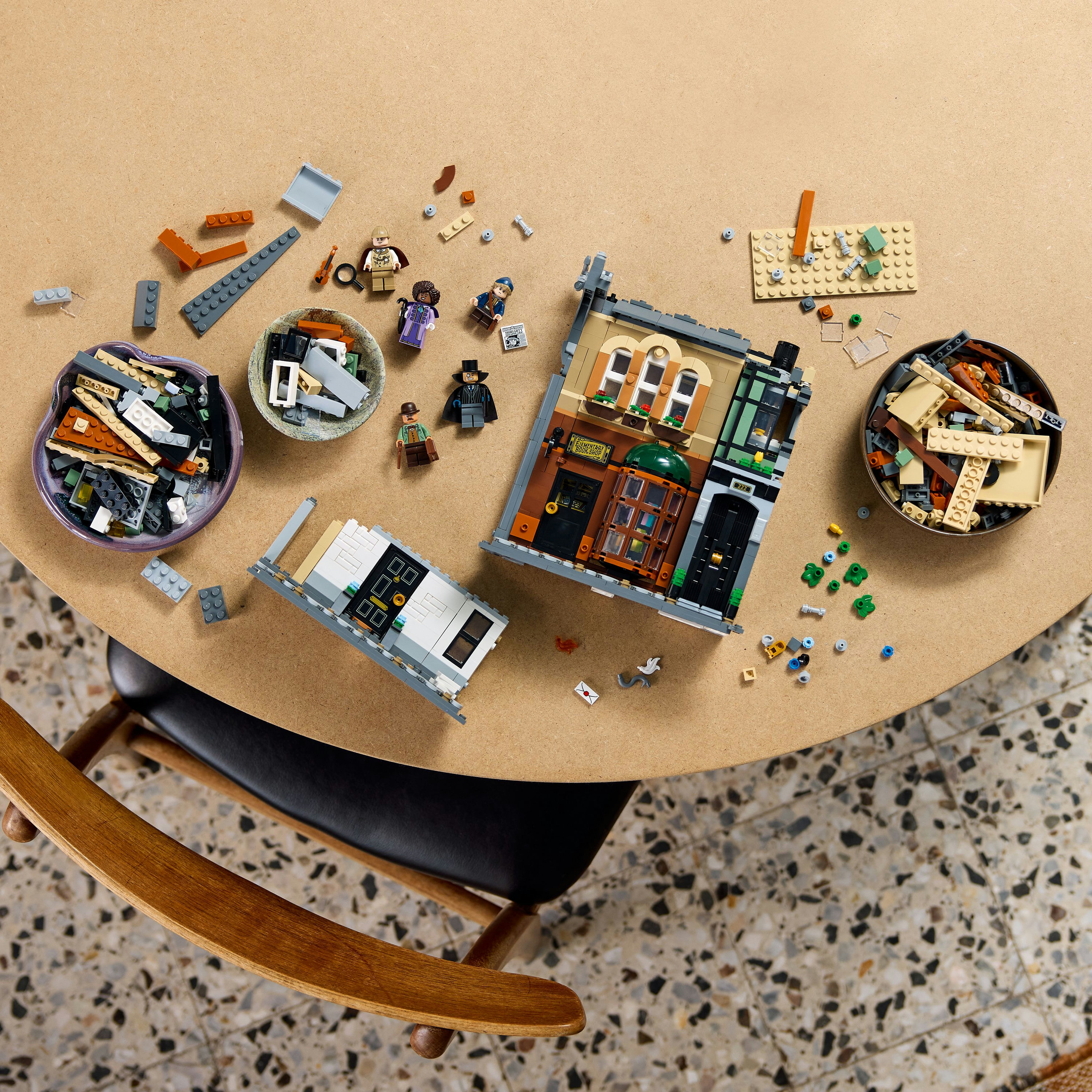 Zestaw Lego na stole z elementami, minifigurkami i gotowymi budynkami. Krzesło na pierwszym planie.