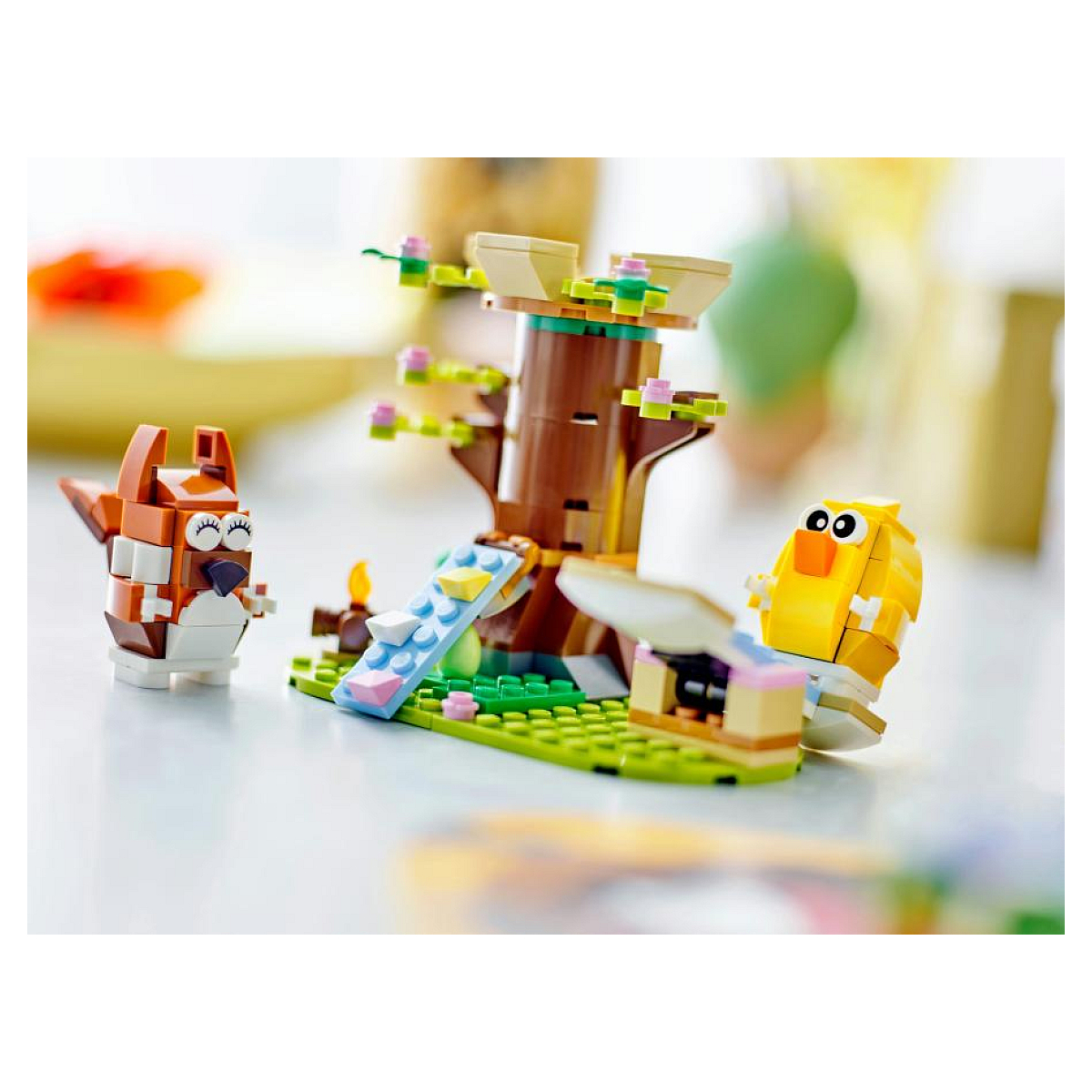 Ağaç, tilki ve civciv içeren Lego seti. Ağaç kahverengi, mavi kaydıraklı. Tilki kahverengi/beyaz, civciv sarı, yeşil taban üzerinde.