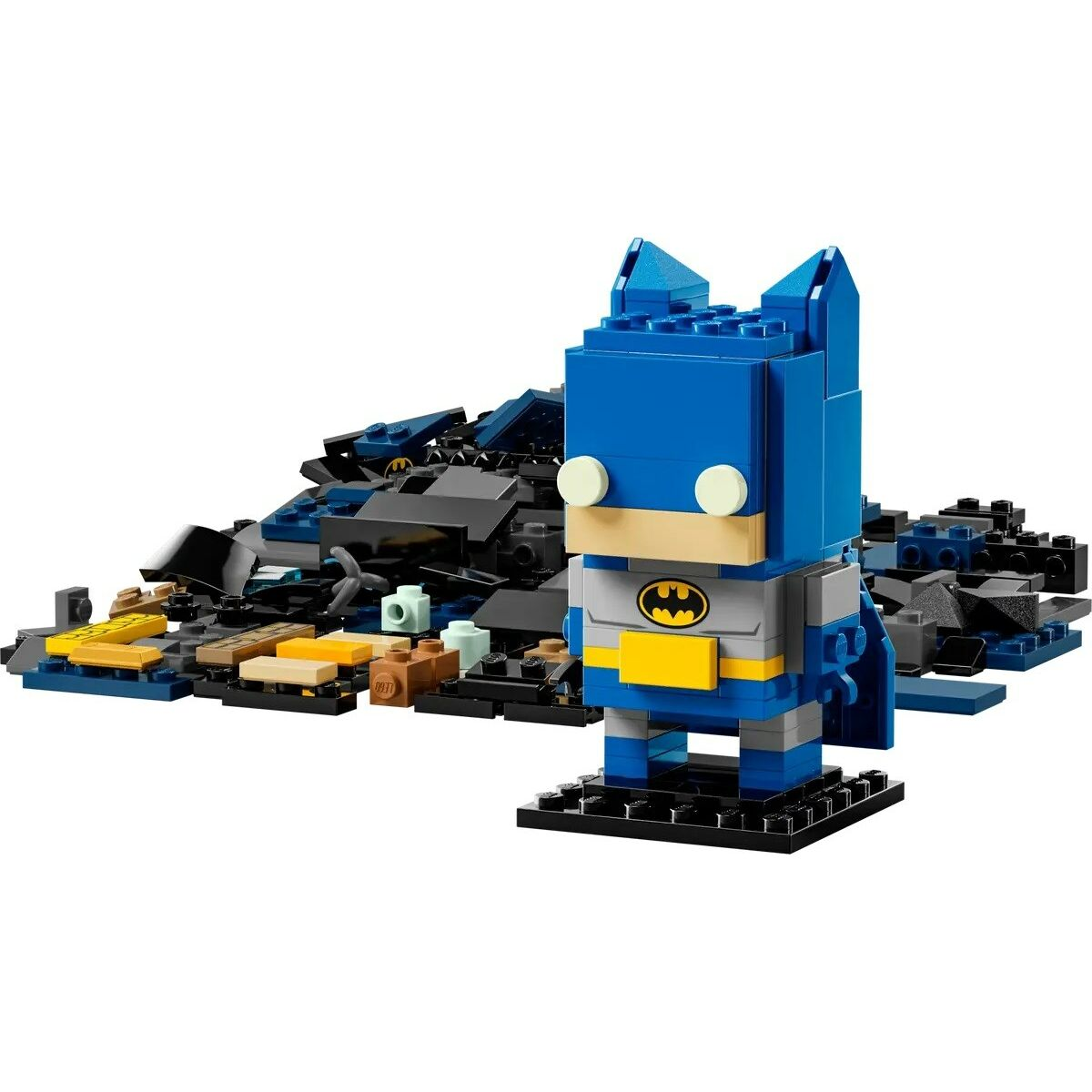 Una figura di Lego Batman è in piedi su una base nera. Dietro c'è un mucchio di mattoncini Lego neri, blu e beige.