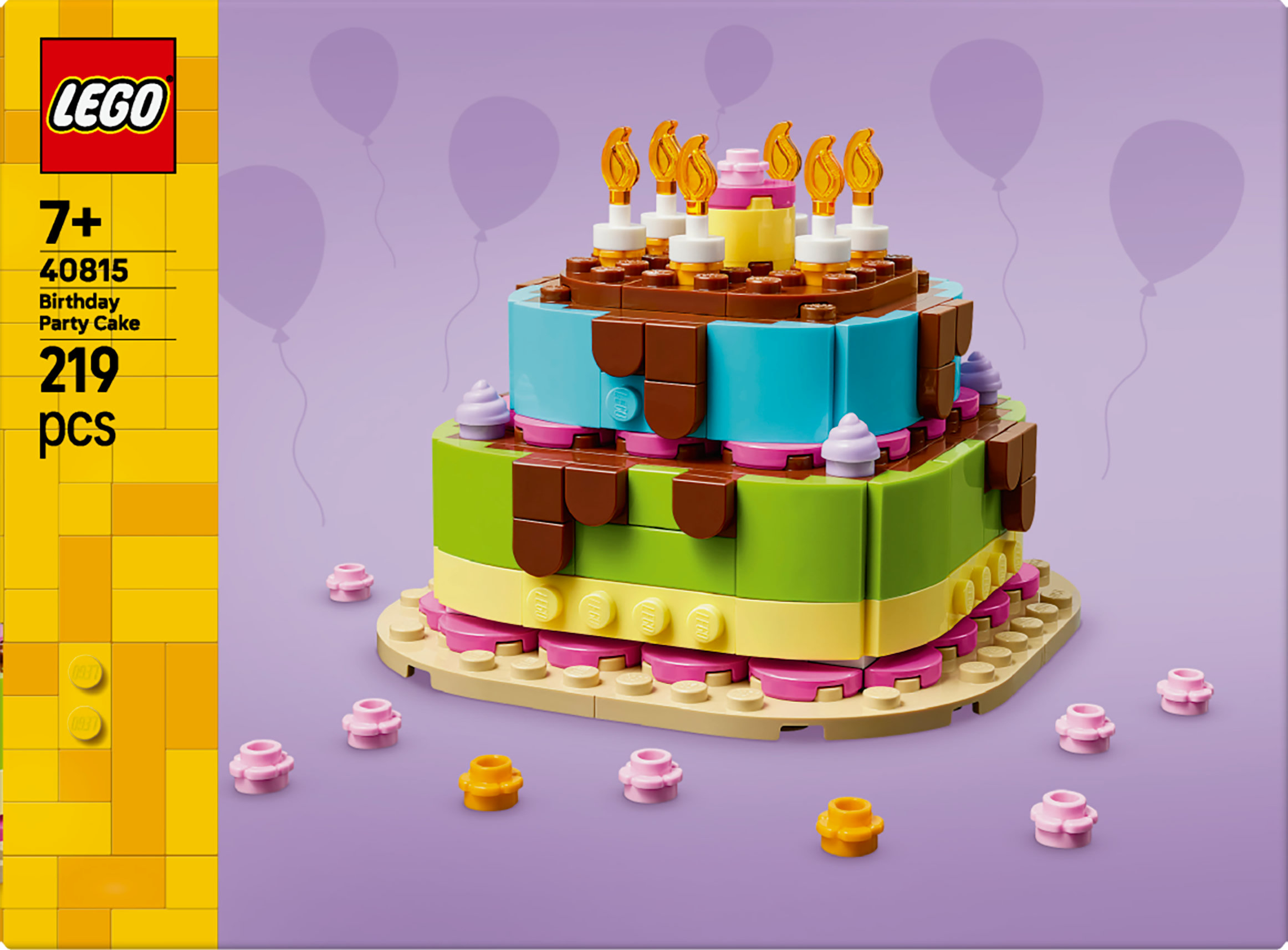 Un set di torta di compleanno Lego. Ha più strati e candele. Palloncini viola sullo sfondo.