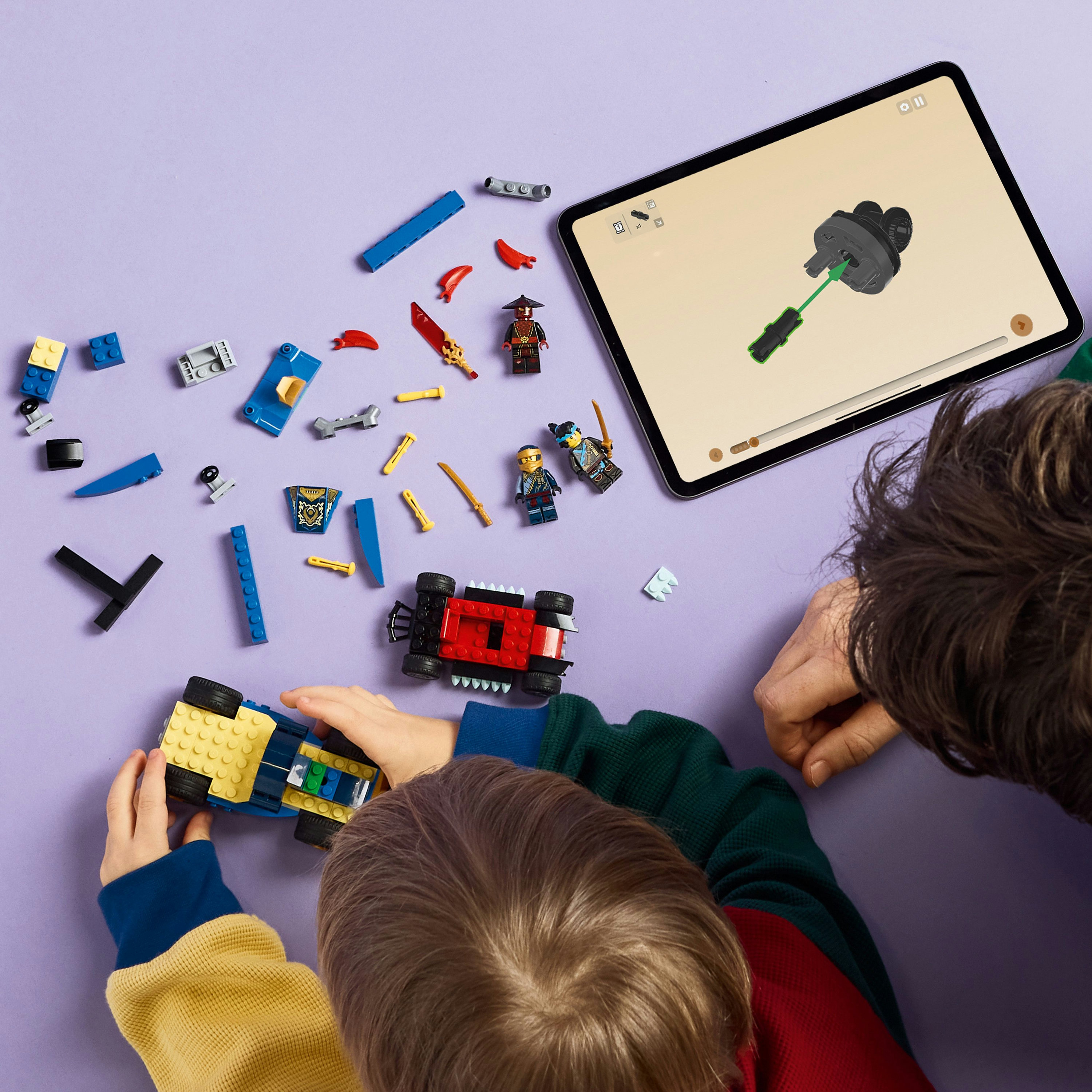 Un bambino costruisce un'auto Lego con le istruzioni su un tablet. Pezzi e figure Lego sparsi su una superficie viola.