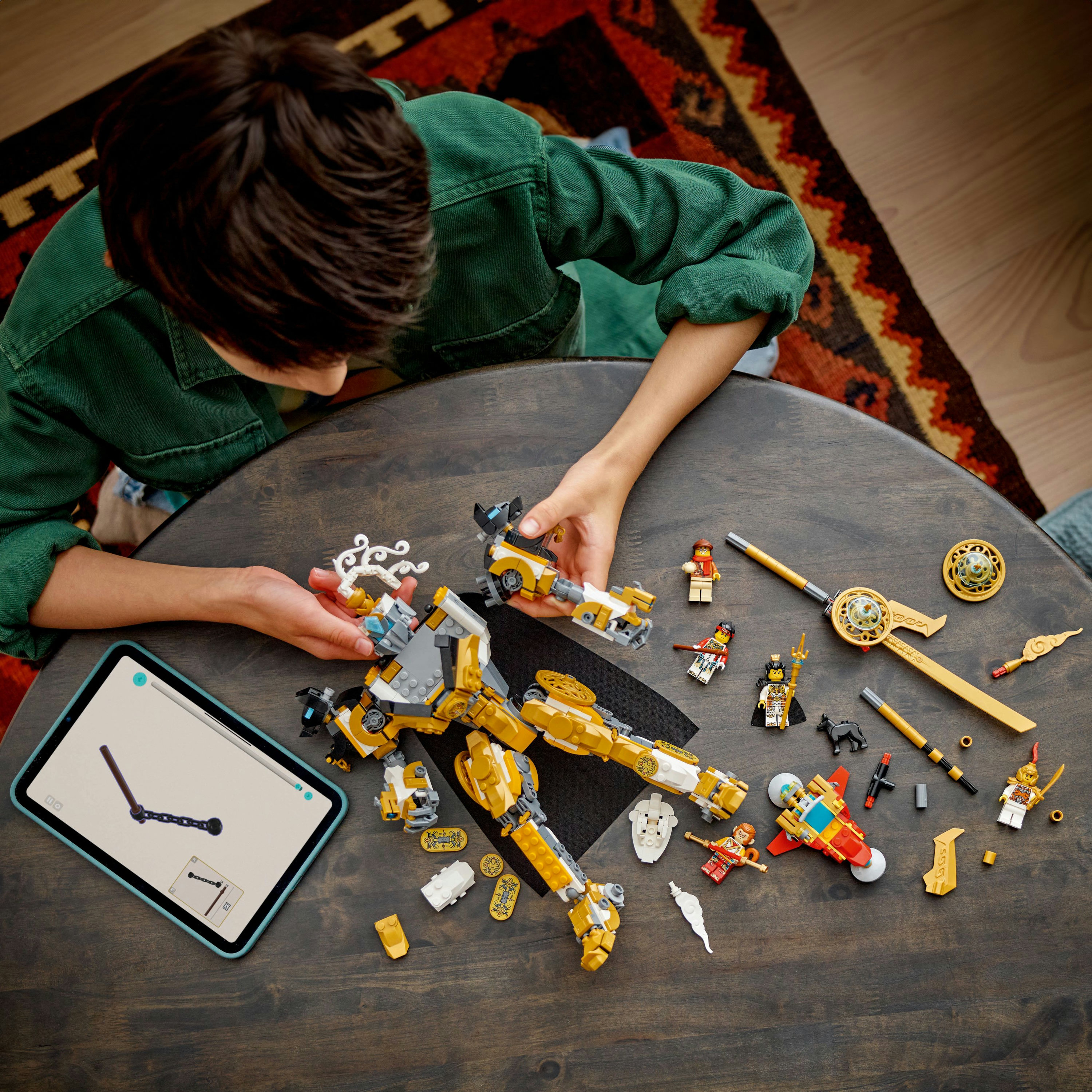 Une personne assemble un ensemble Lego sur une table. L'ensemble comprend un grand robot et des figurines.