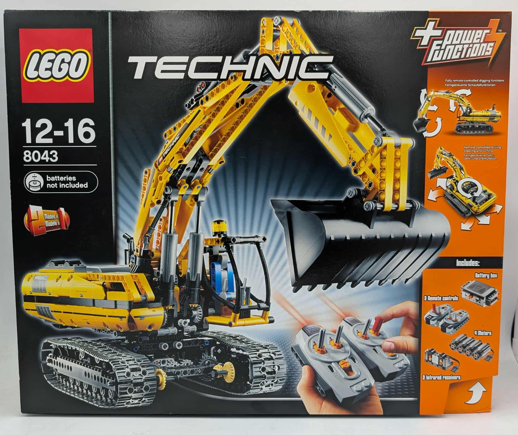 Lego Technic graafmachine doos. Geel graafmachine model op zwarte achtergrond. Inclusief afstandsbedieningen, batterijbox en motoren.