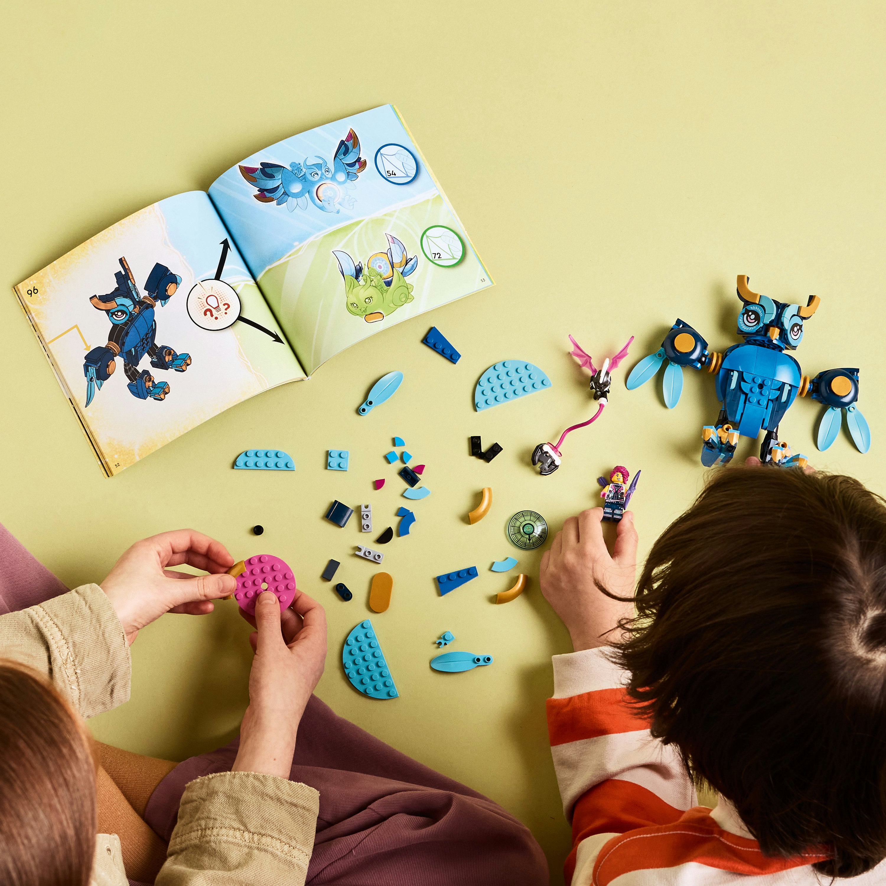 Twee mensen die een Lego-set in elkaar zetten. Blauwe uilachtige figuur en bouwinstructies zijn zichtbaar op een gele ondergrond.