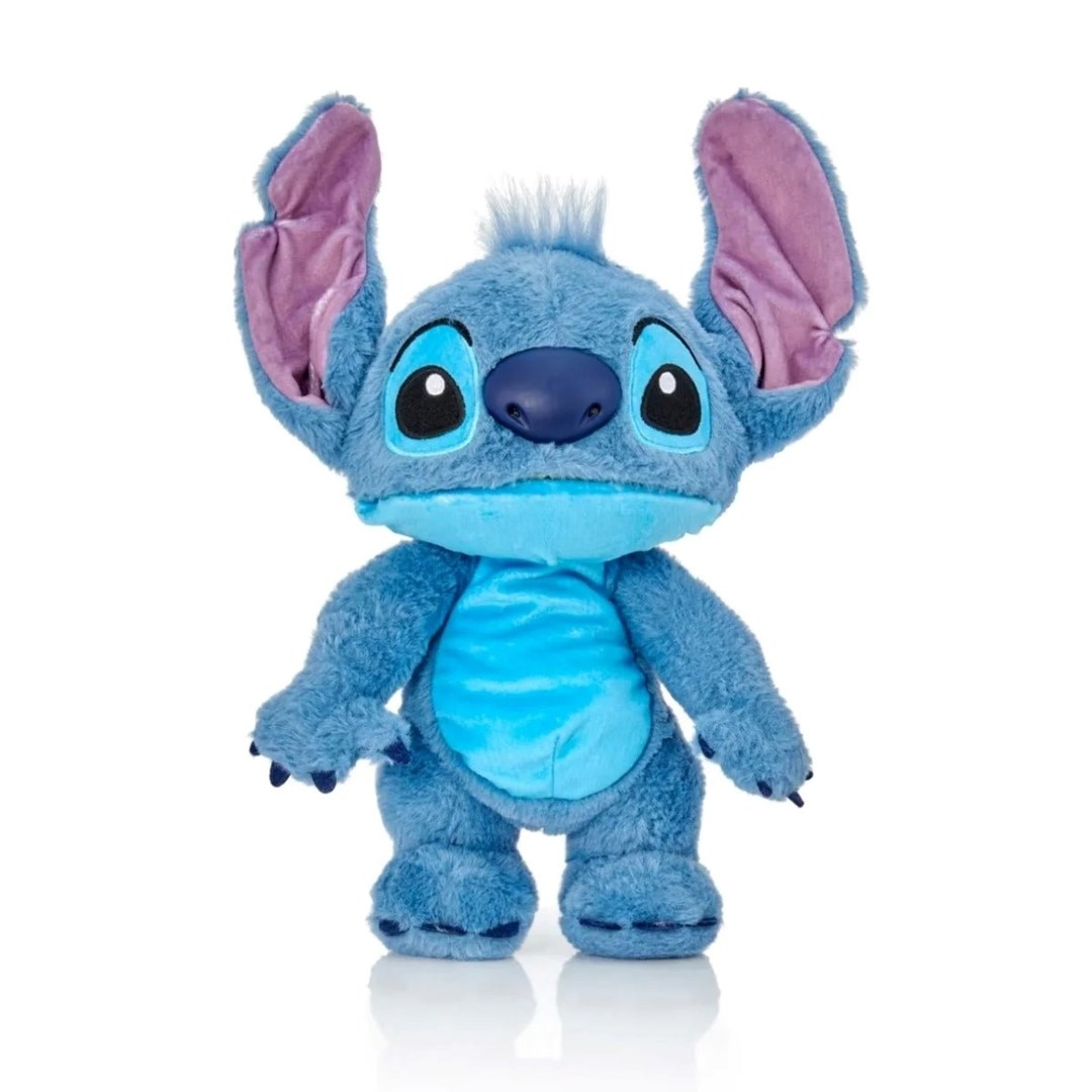 Niebieska pluszowa zabawka Stitch stoi na białym tle. Ma duże uszy, duże oczy i niebieski korpus z jaśniejszym brzuchem.