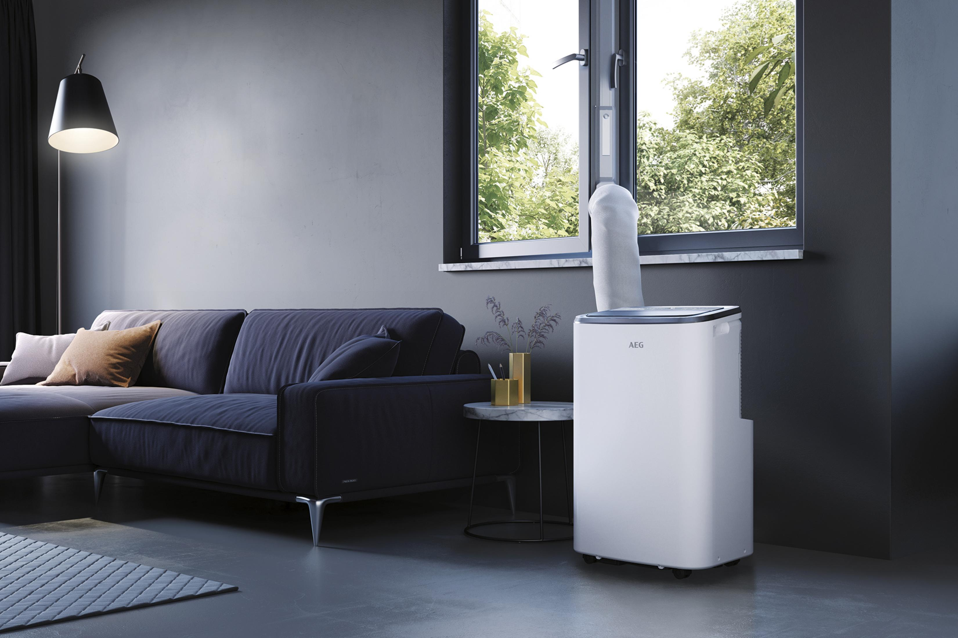 Modernes Wohnzimmer mit marineblauem Sofa, AEG-Klimaanlage am Fenster und Stehlampe.