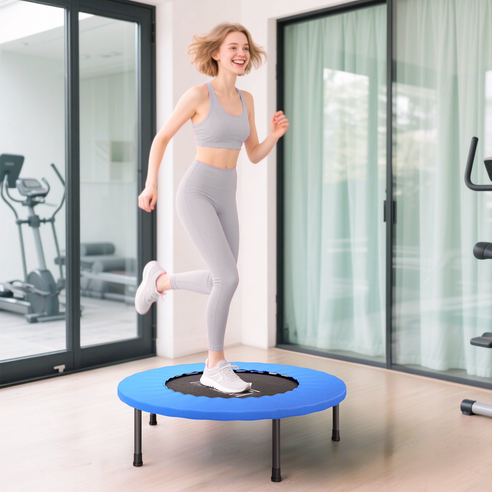 Una mujer con ropa deportiva salta sobre un trampolín azul en un gimnasio. Otro equipo de ejercicio está en el fondo.