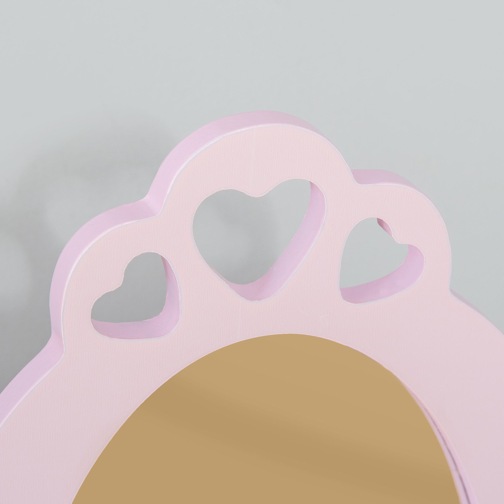 Un marco de espejo rosa en forma de corazón con superficie de espejo marrón claro, sobre fondo gris.
