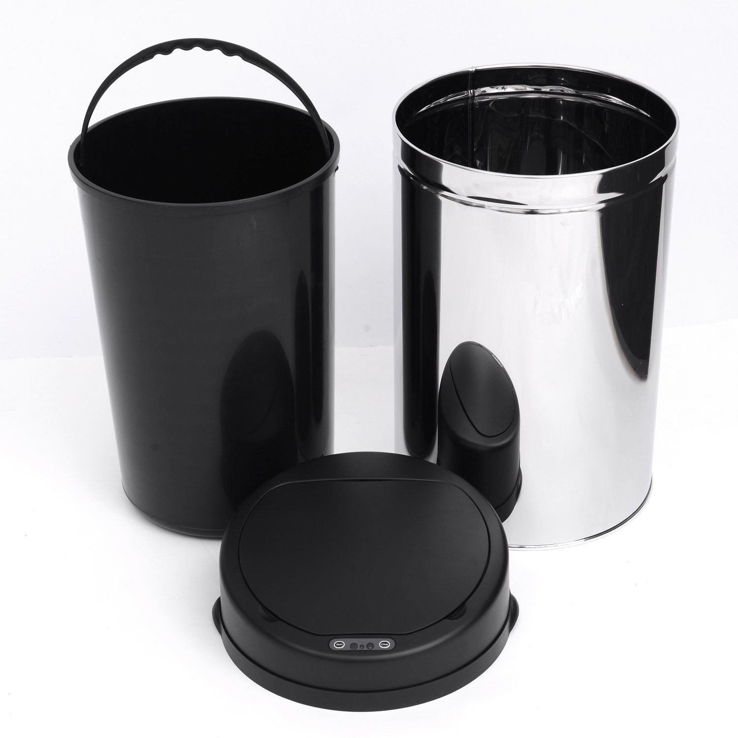 Tres botes de basura: cubo negro con asa, bote de acero inoxidable y tapa negra con botones, todo sobre una superficie blanca.