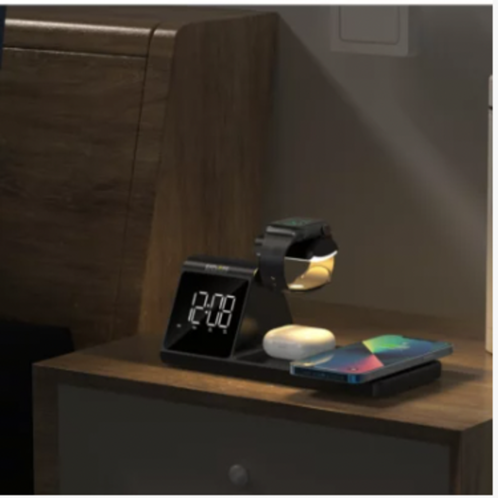 Un comodino con orologio, Apple Watch, auricolari e telefono. L'orologio segna le 12:08. L'orologio è in carica. Il telefono mostra uno schermo colorato.