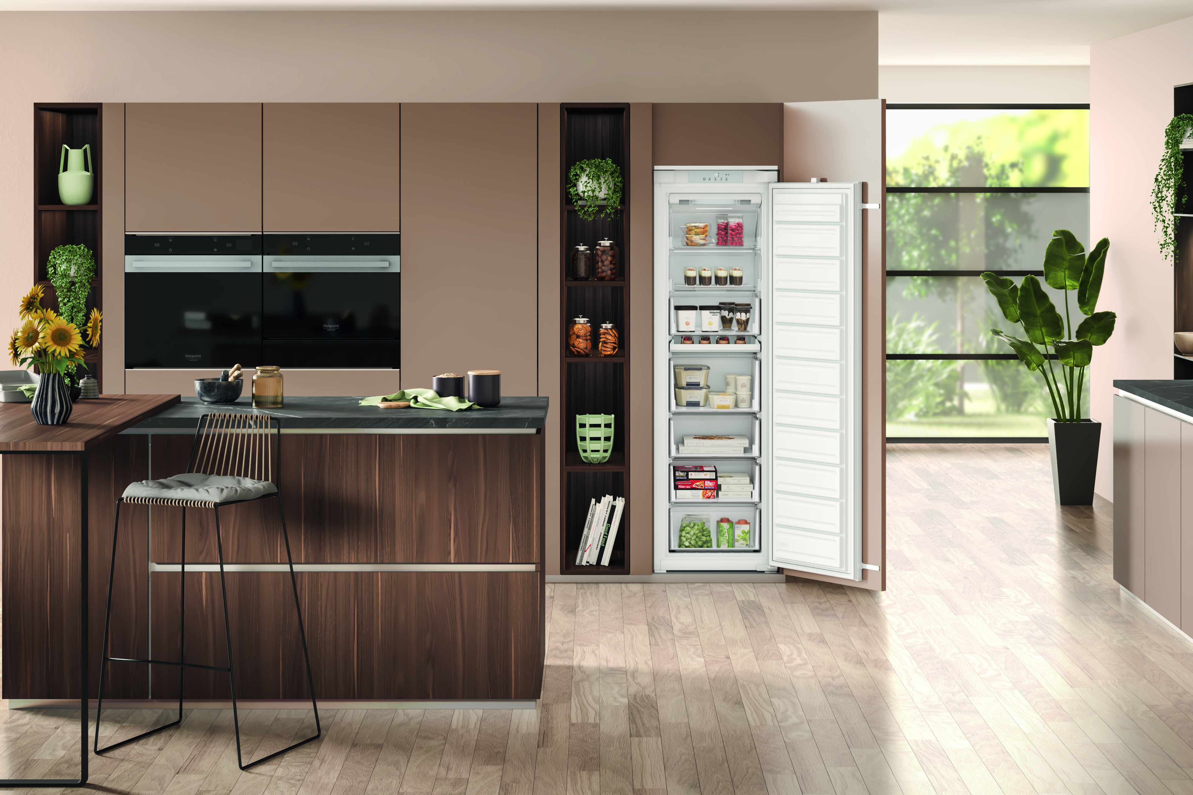Interior de cocina moderna con nevera abierta. Taburete frente a mostrador con flores.