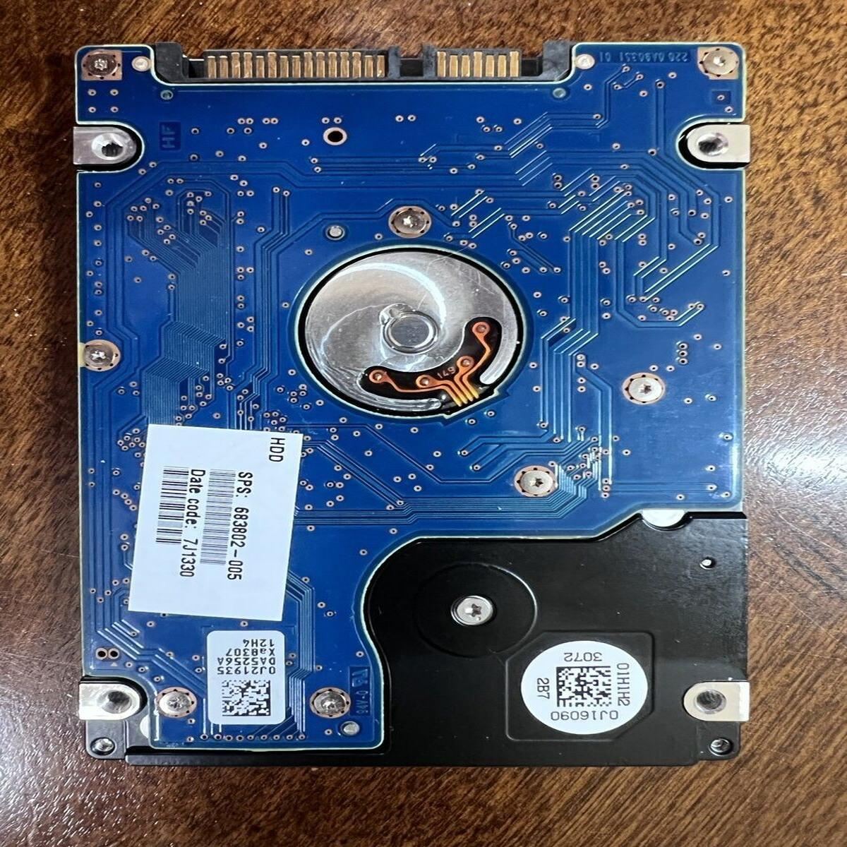 Disco rigido con circuito blu su legno. Etichette con codici, componenti metallici e connettori sono visibili.