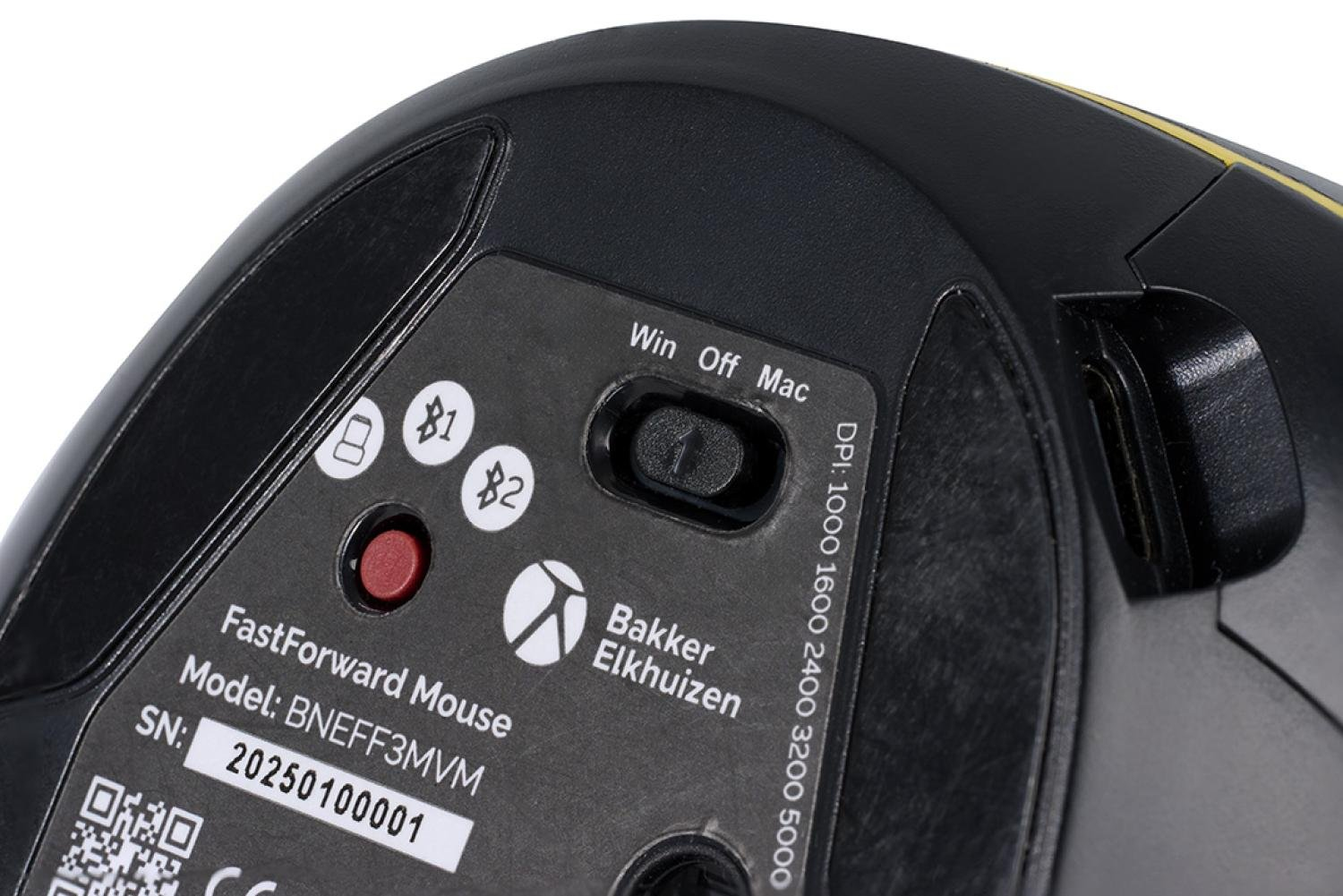 Primer plano de la parte inferior de un ratón de ordenador negro. Se ven botones, un interruptor, una etiqueta con el modelo y el número de serie, y el logotipo de Bakker Elkhuizen.