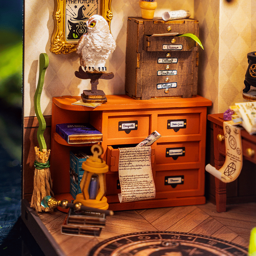 Miniaturowe studio czarownicy z posągiem sowy, szufladami z nazwami eliksirów, miotłą, latarnią i zwiniętymi zwojami.