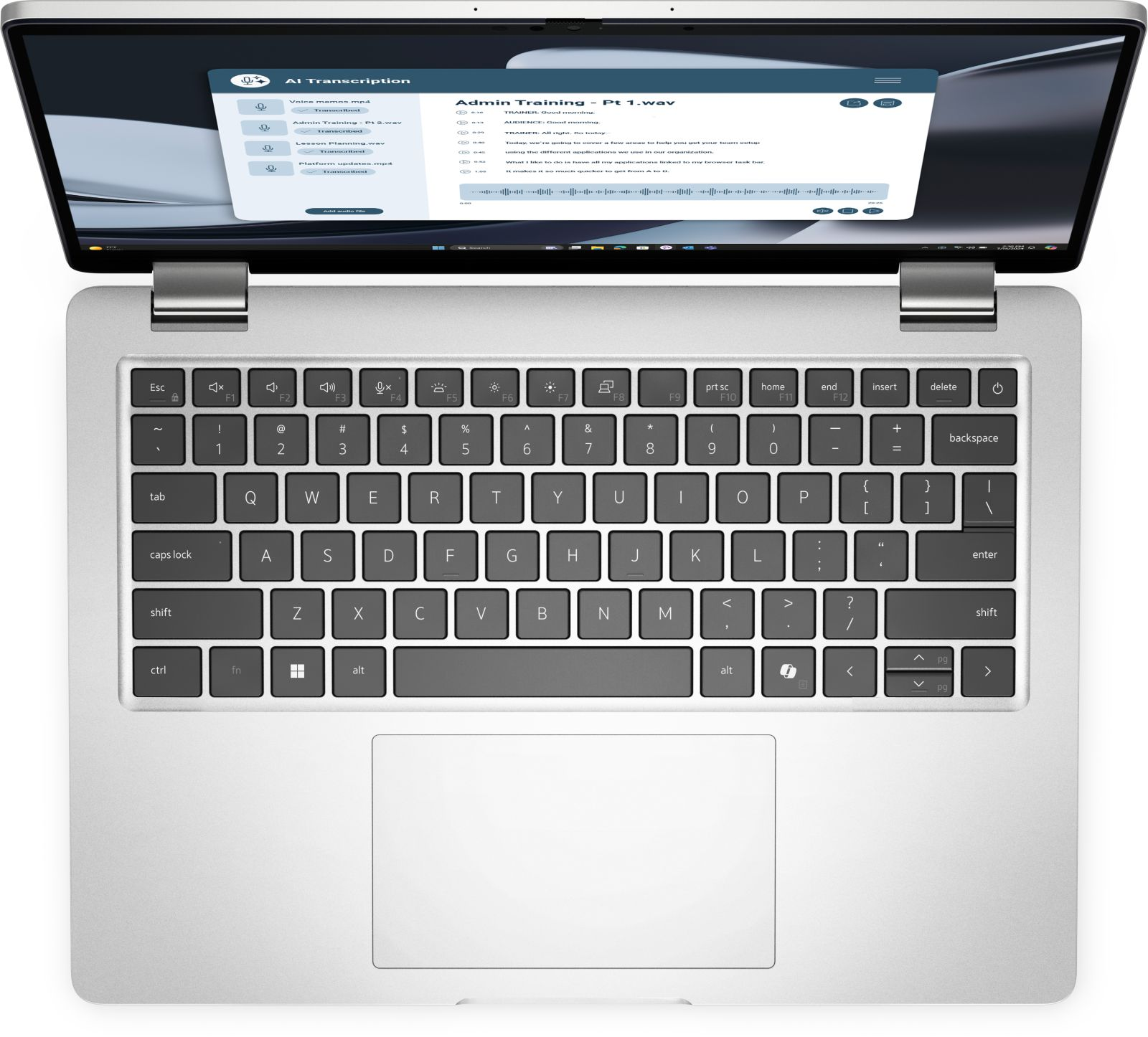 Ein Laptop ist geöffnet und zeigt eine Transkriptionsoberfläche. Die Tastatur ist sichtbar und der Bildschirm zeigt Audiowiedergabesteuerelemente.