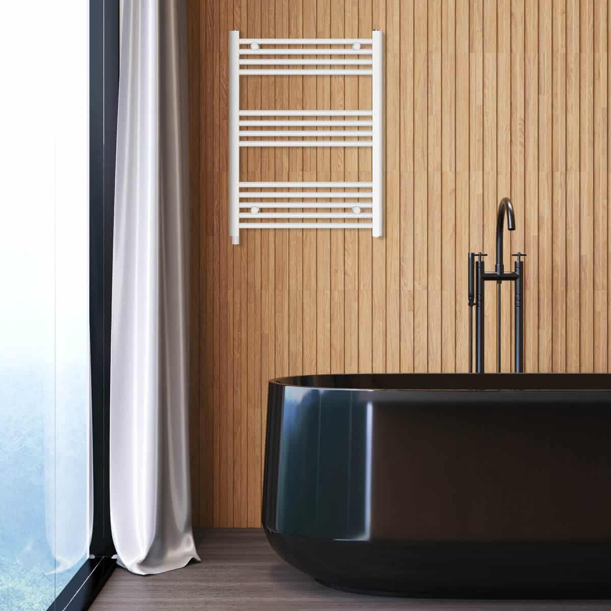 Łazienka z czarną wanną, białym wieszakiem na ręczniki, czarną baterią i drewnianą ścianą. Po lewej okno z białym zasłoną.