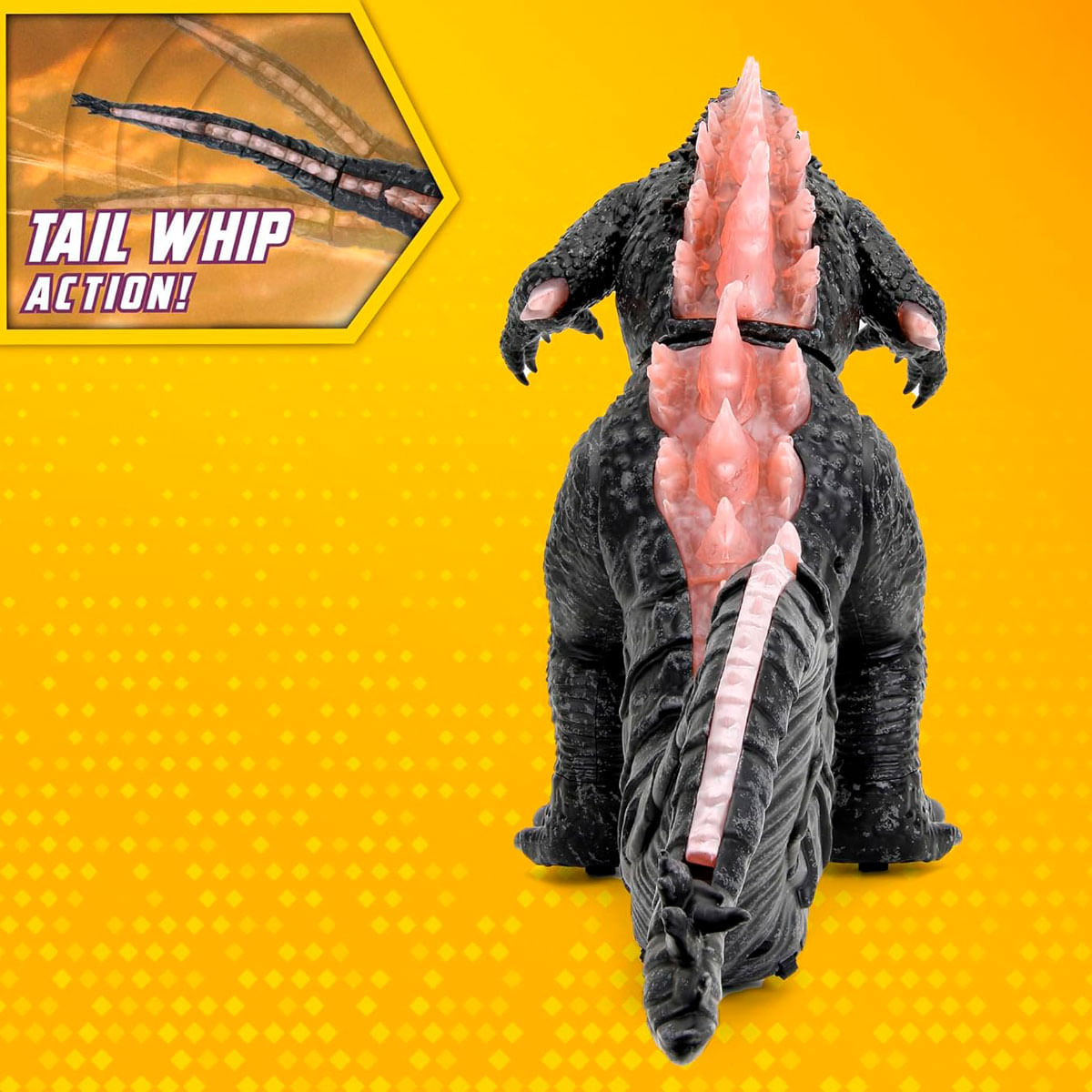 Ein schwarzes Godzilla-Spielzeug mit rosa Rückenflossen und Schwanz. Der Hintergrund ist gelb mit einem Rautenmuster und einer "TAIL WHIP ACTION!" Box.