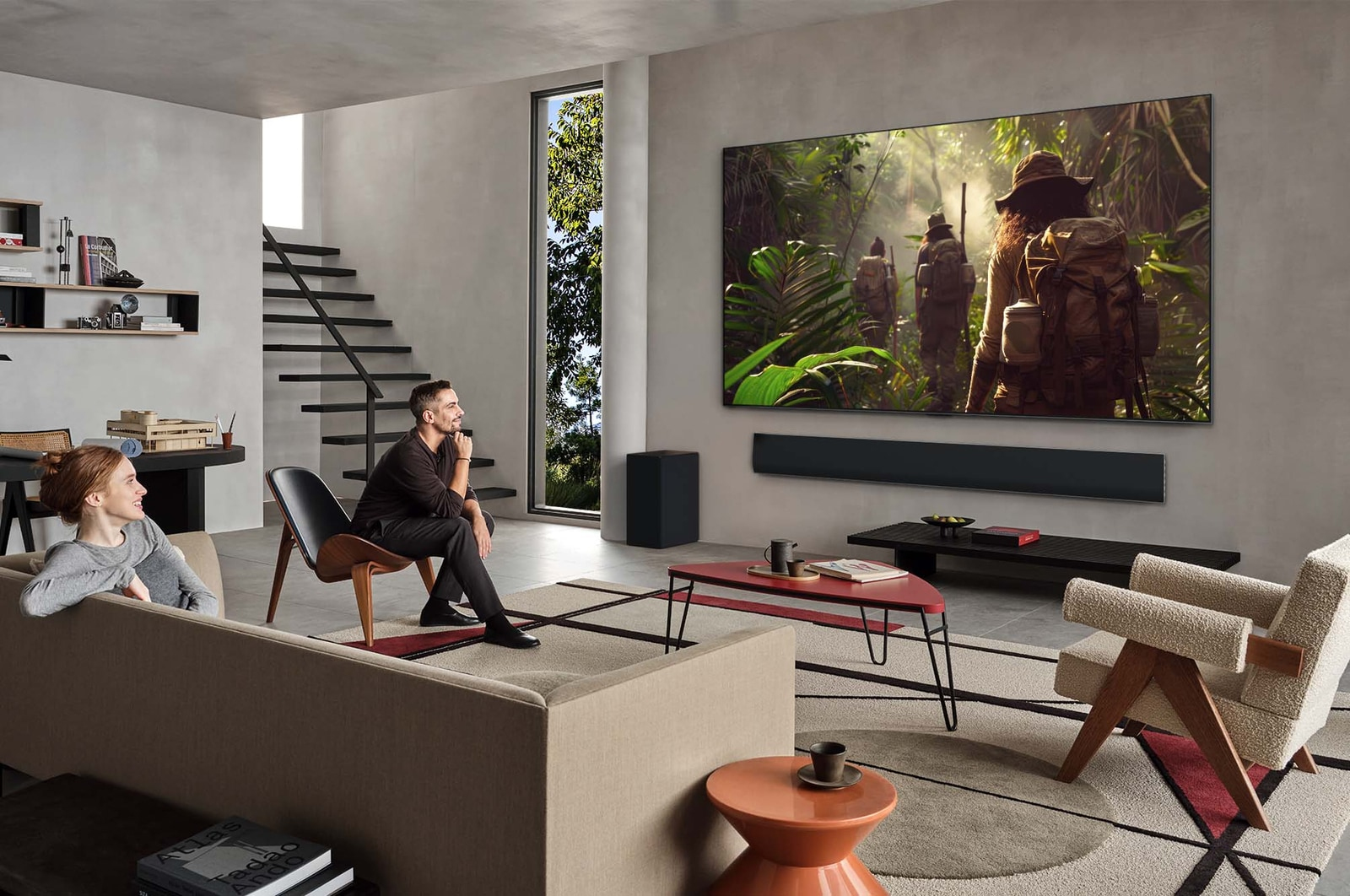 Büyük bir TV'de orman sahnesi gösteren modern bir oturma odası. Bir erkek ve bir kadın oturuyor, ekranı izliyor.