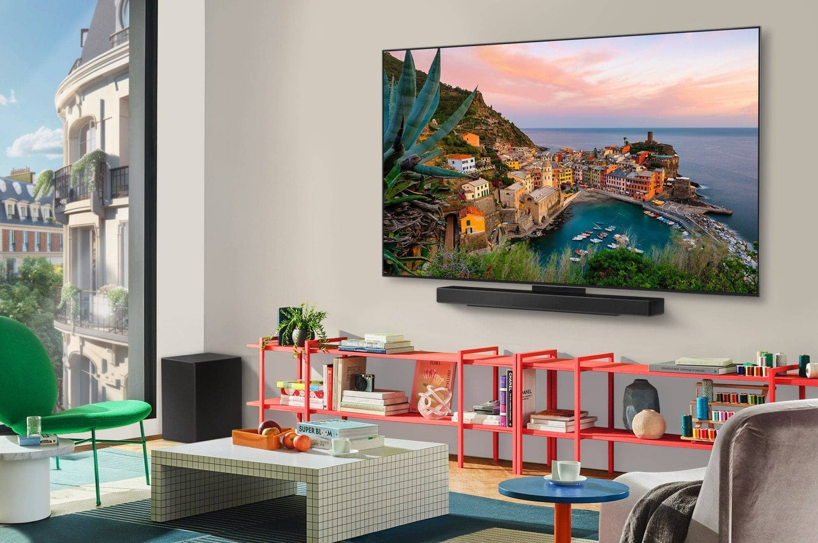 Sahildeki bir kasaba sahnesini gösteren büyük bir TV'li oturma odası. Kırmızı raflarda kitaplar ve dekorlar. Şehir manzaralı pencere.