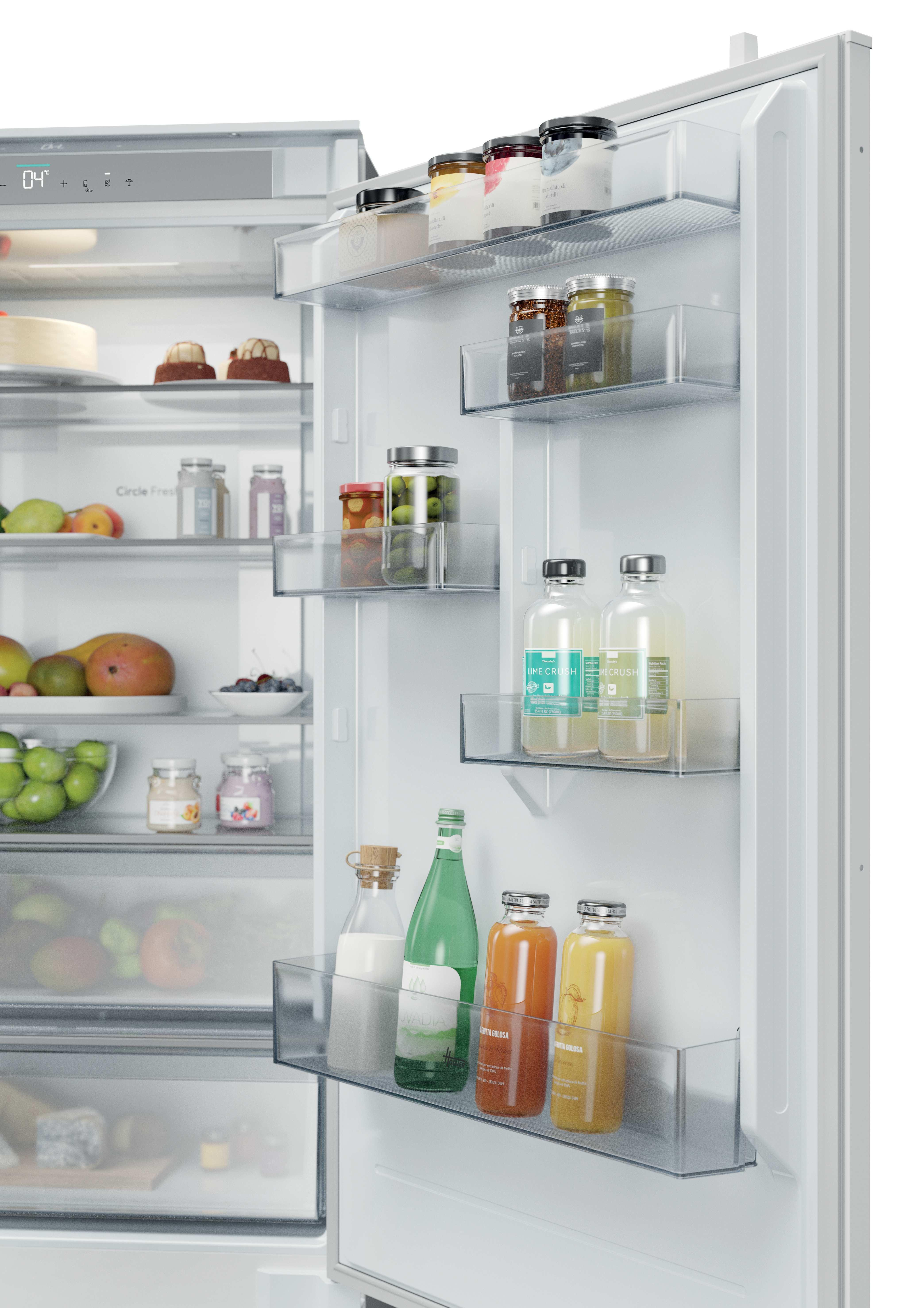 Refrigerador abierto con frascos de comida, botellas de bebidas, frutas y pasteles en estantes.